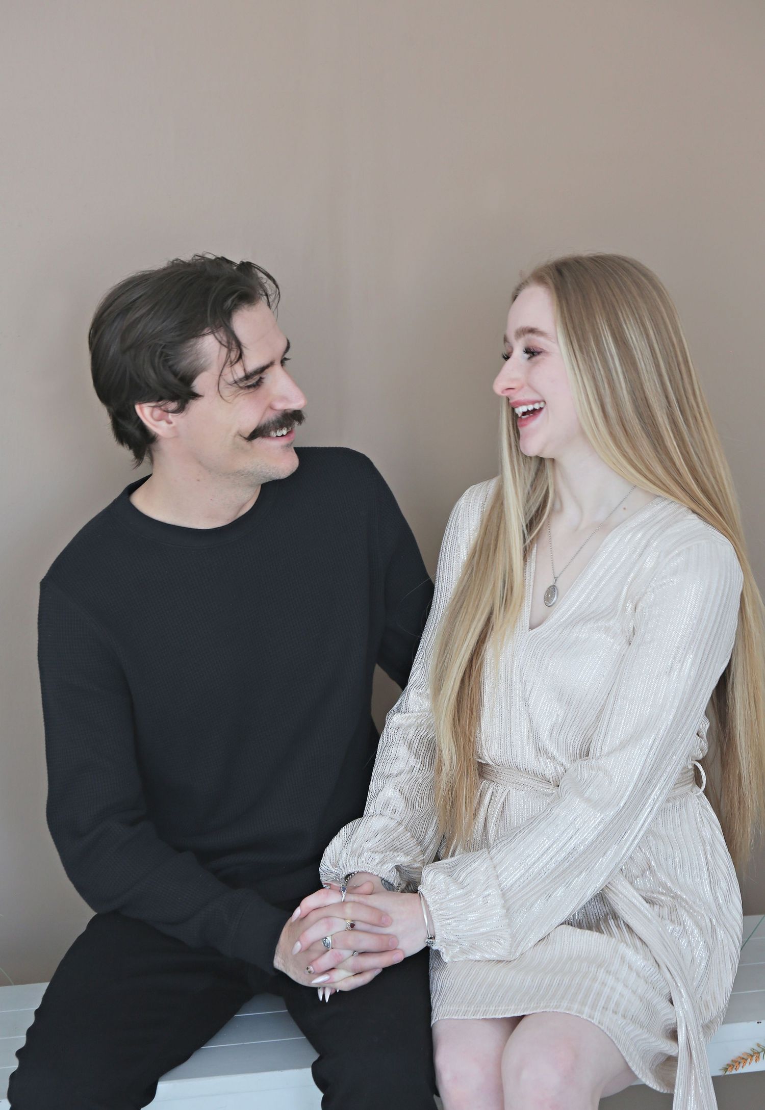 Happy couple shares a joyful moment while sitting together in a bright indoor setting.