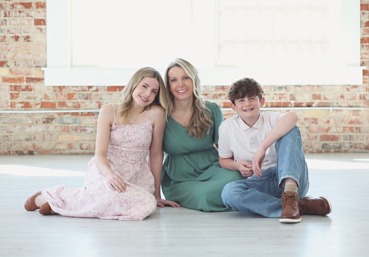 Casual indoor family portraits against a rustic brick wall backdrop.