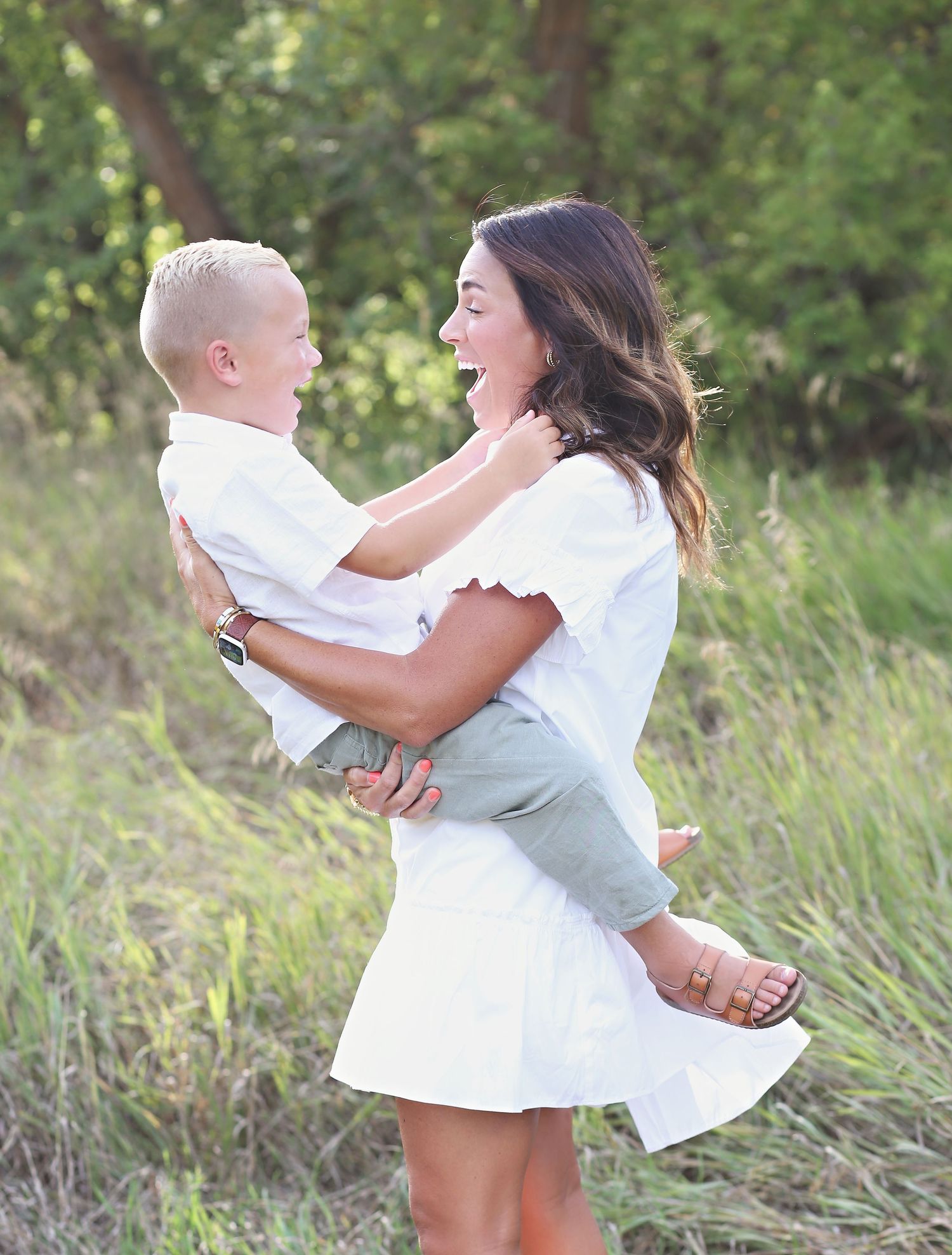 Playful spinning and hugging moments captured in outdoor setting with tall grass.