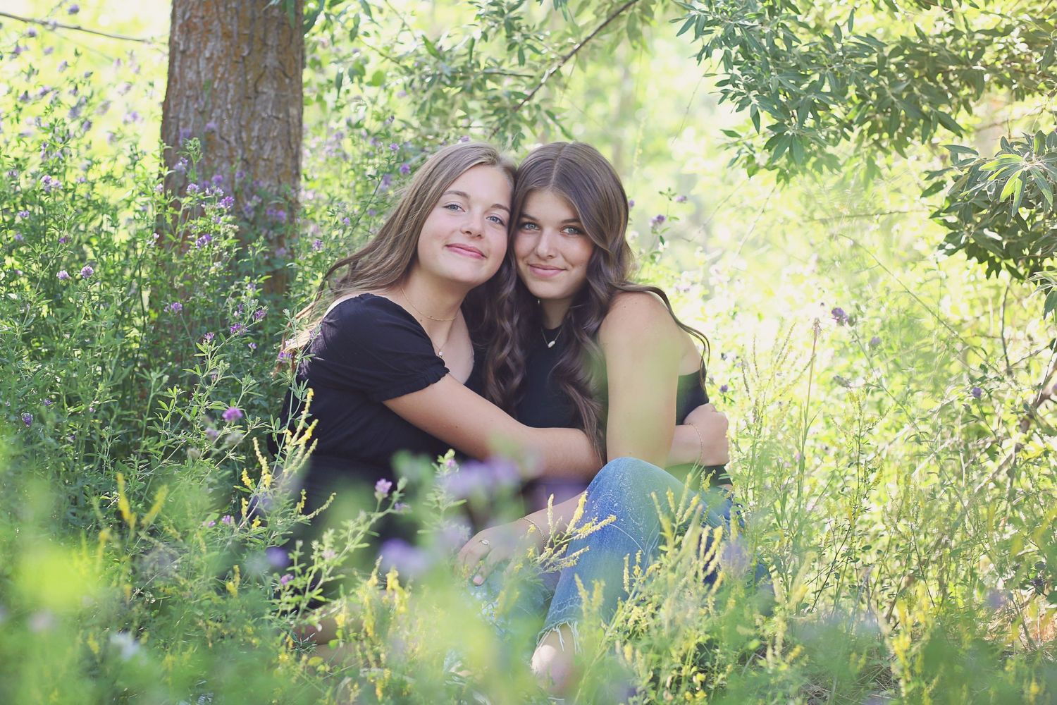 Two people sharing warm embraces while sitting in a lush outdoor setting with natural lighting.