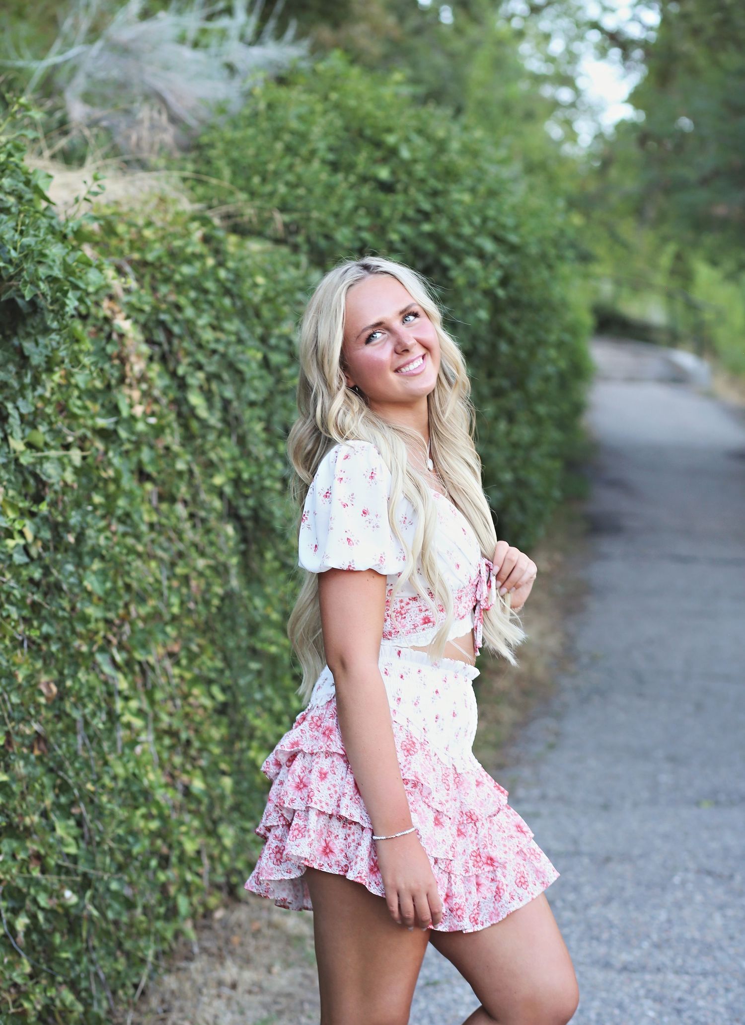 Summer fashion portrait along a garden path with flowering bushes.