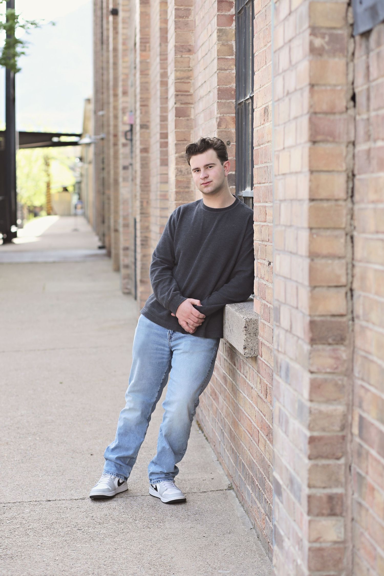 Casual street style portrait against brick wall in urban setting.
