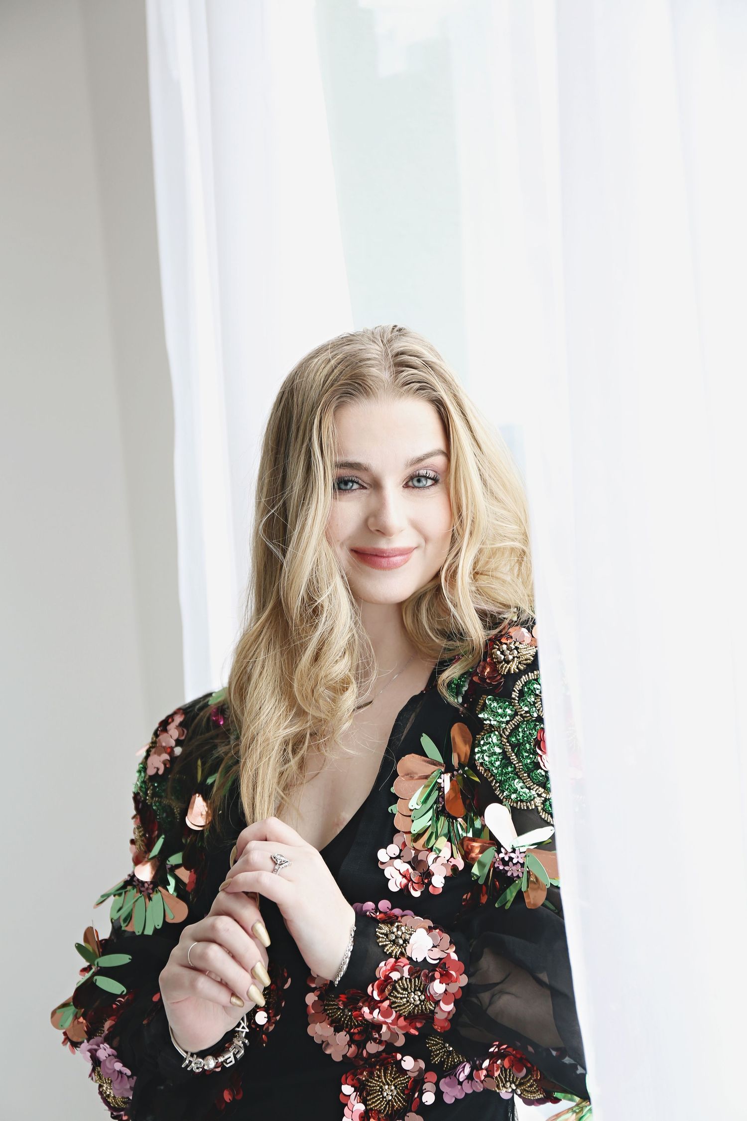 Indoor portrait with white backdrop wearing floral print black dress.