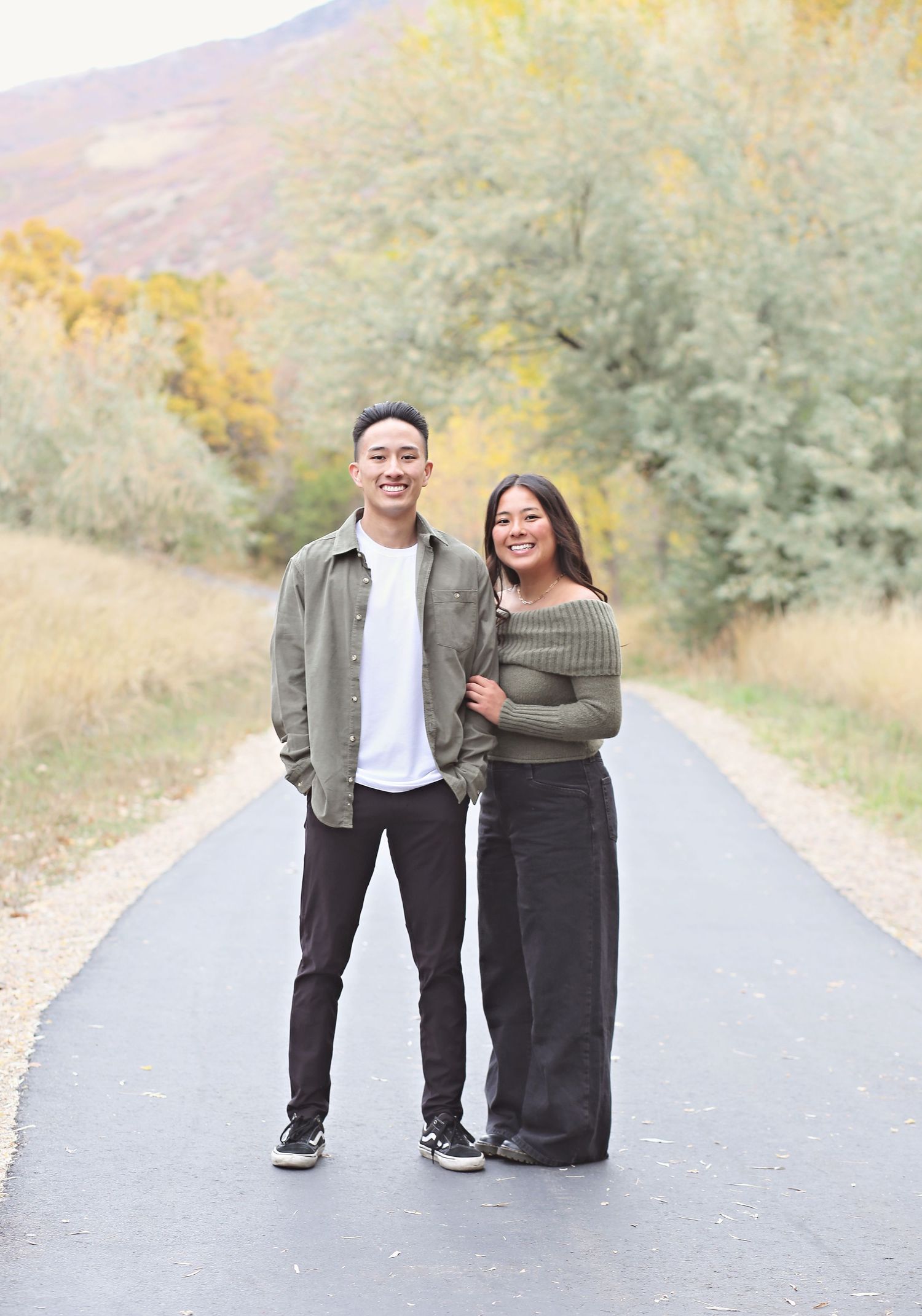 Group portrait session on a paved road surrounded by autumn foliage and natural scenery.