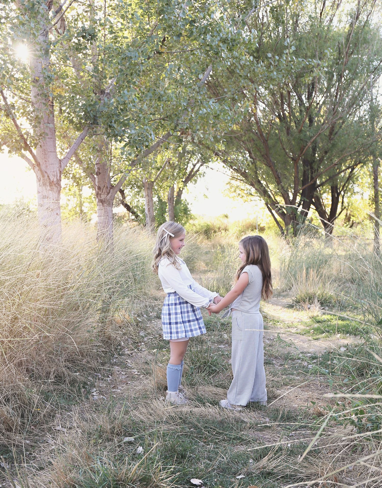 Children playing and posing together in a natural outdoor setting with trees.