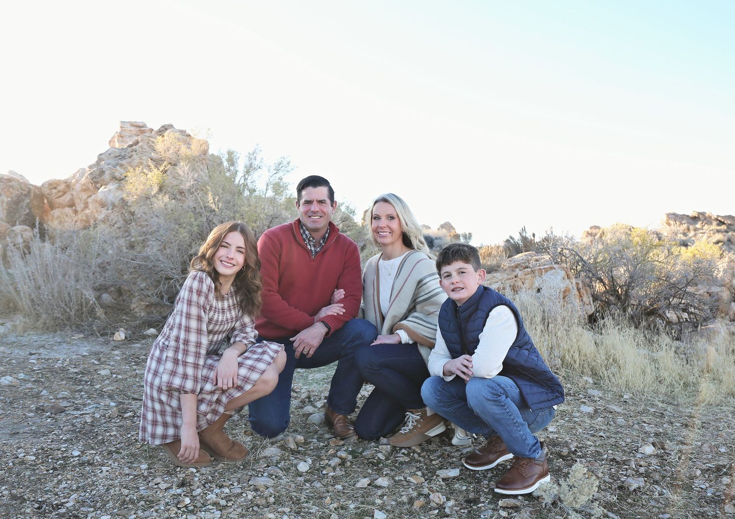 Family photo session on rocky terrain with desert landscape in background.