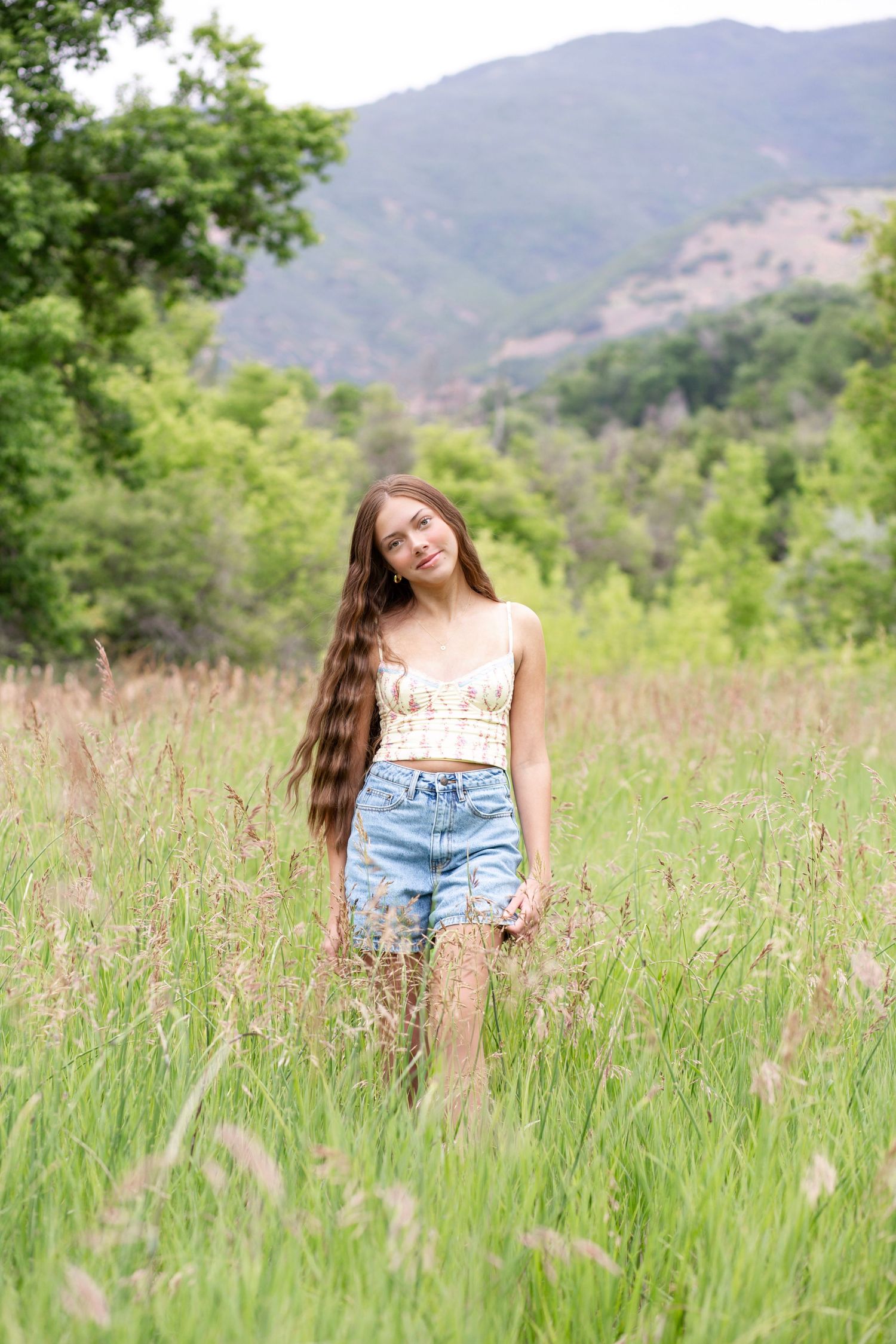 Bohemian style portrait in mountain meadow with flowing tall grass and natural lighting.