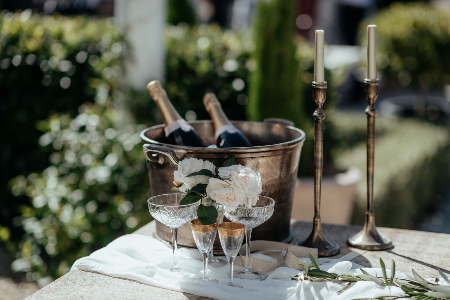 Champagne bottles in a bucket with glasses and candles outside on a tablescape in Martinborough by August and Vine