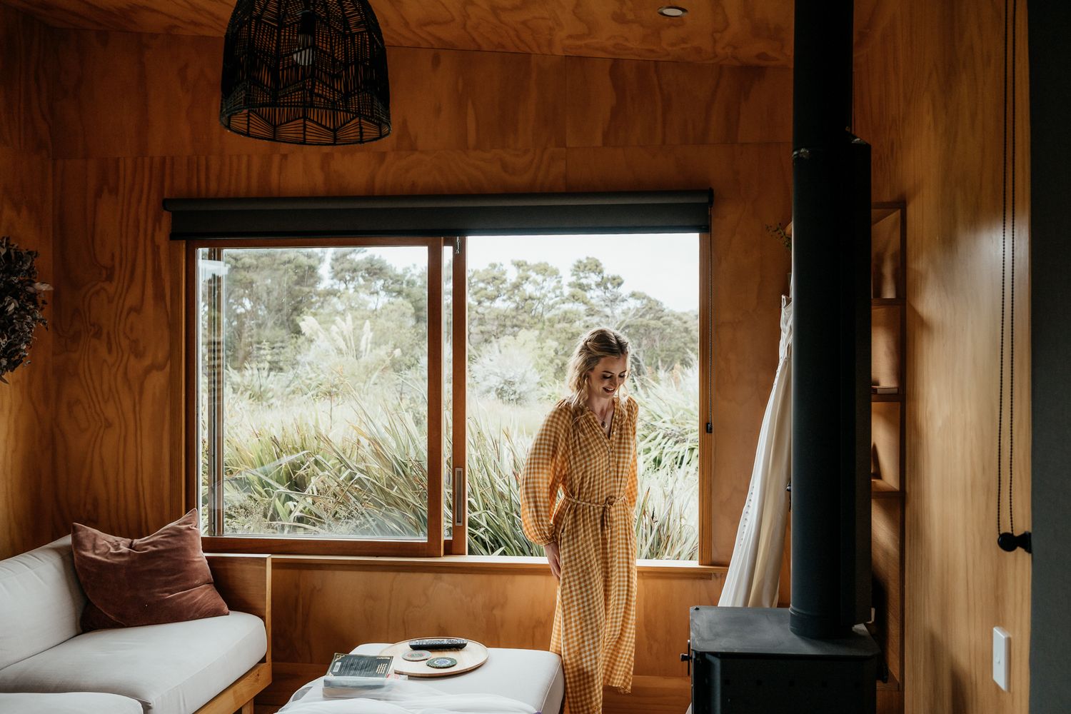 A cozy wooden cabin interior with a window view, wood paneling, and rustic decor details at Whitimanuka by August and Vine
