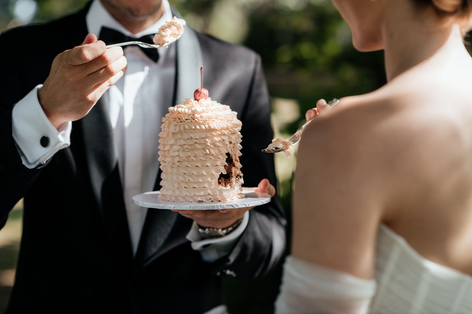 An eloping couple share a vintage mini wedding cake at their outdoor elopement during a sunny day by August and Vine.