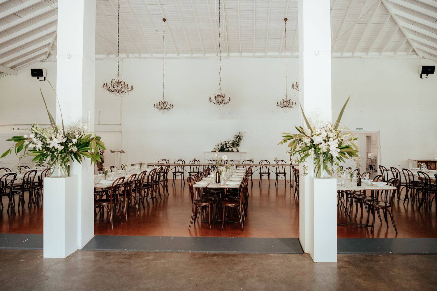 A spacious white reception hall with bentwood chairs and long dining tables at Rose and Smith Wairarapa by August & Vine