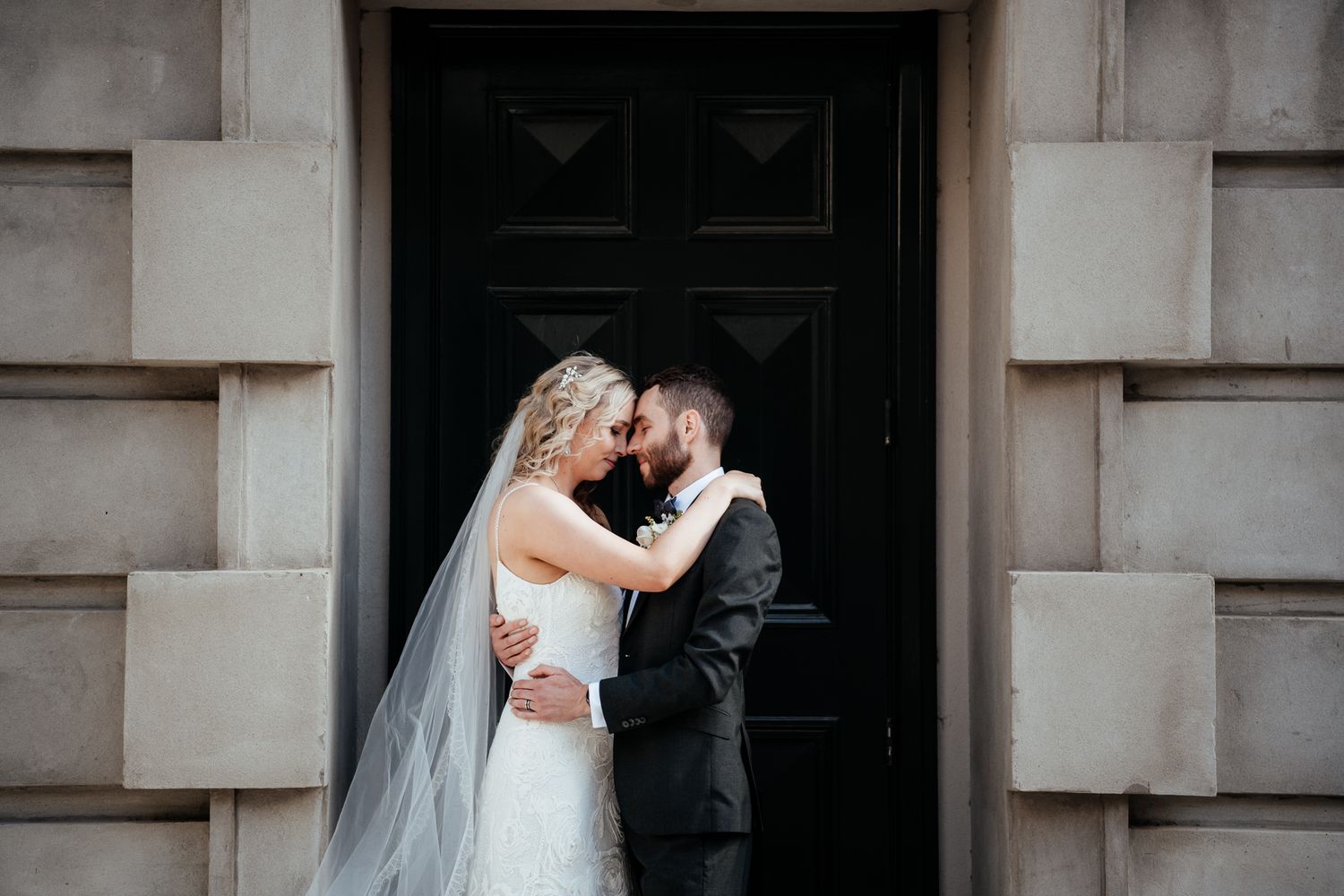Bride and Groom embrace in a stone doorway outside Old Parliament Wellington by August and Vine