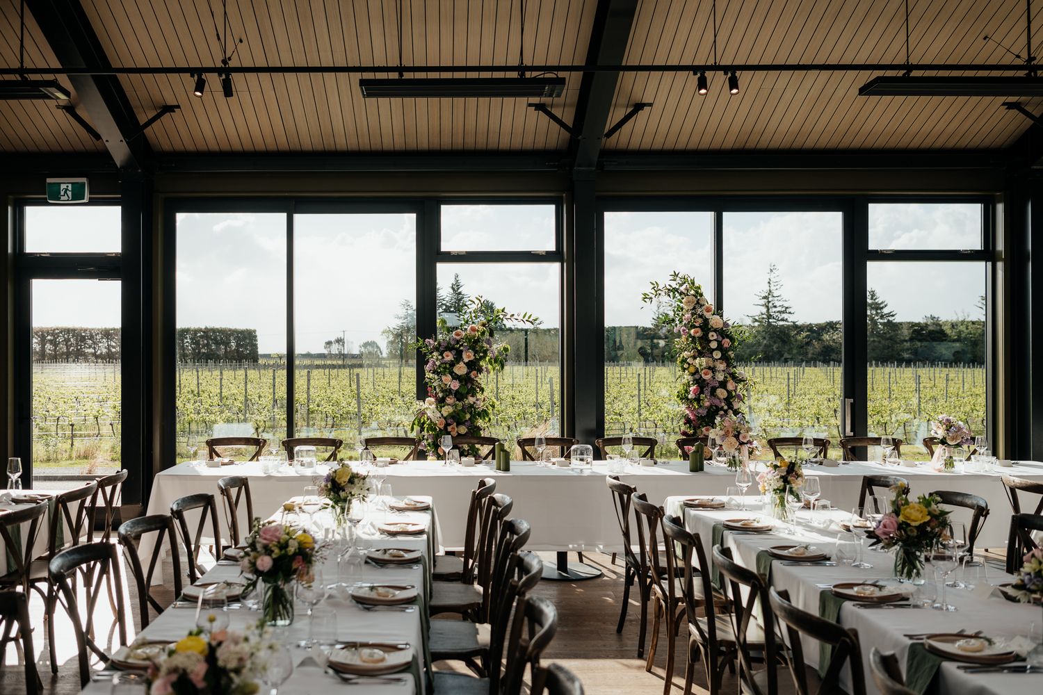 Modern venue The Runholder with elegant wedding table settings and large windows overlooking Te Kairanga Vineyard by August and Vine