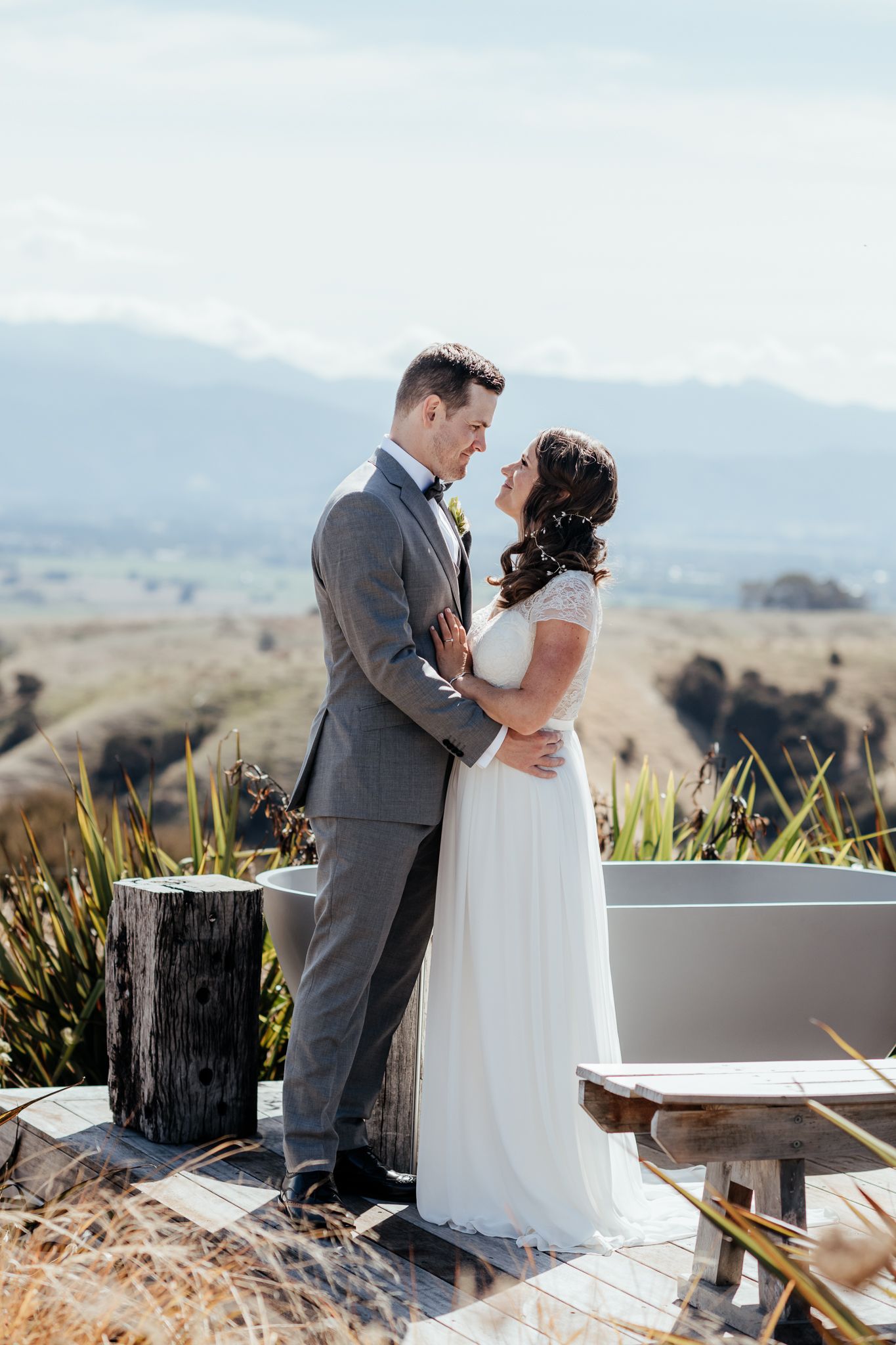 A couple shares an intimate moment on their wedding day overlooking scenic mountain vistas on a sunny day at Whitimanuka by August and Vine