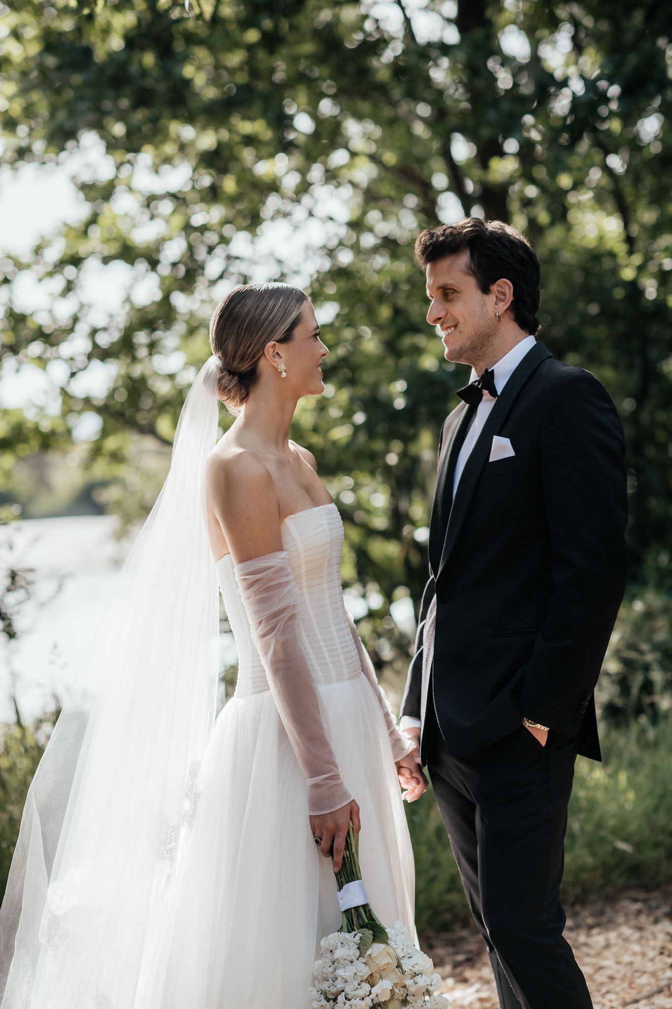 A bride and groom share a tender moment at Rototawai with beautiful bokeh lighting and natural greenery in the background by August and Vine