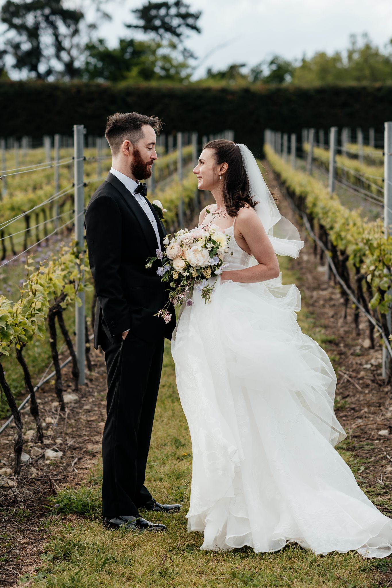 A wedding couple share romantic moments among vineyard rows at The Runholder by August and Vine