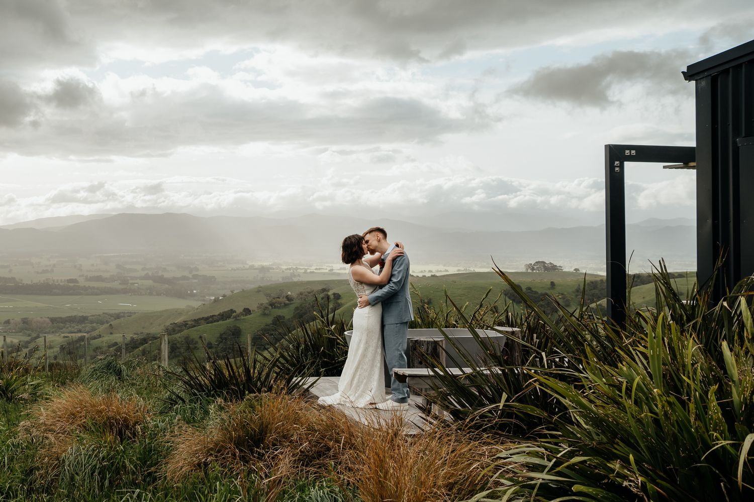 A scenic panoramic view of rolling hills and valley under dramatic cloudy skies at Whitimanuka in Wairarapa by August and Vine