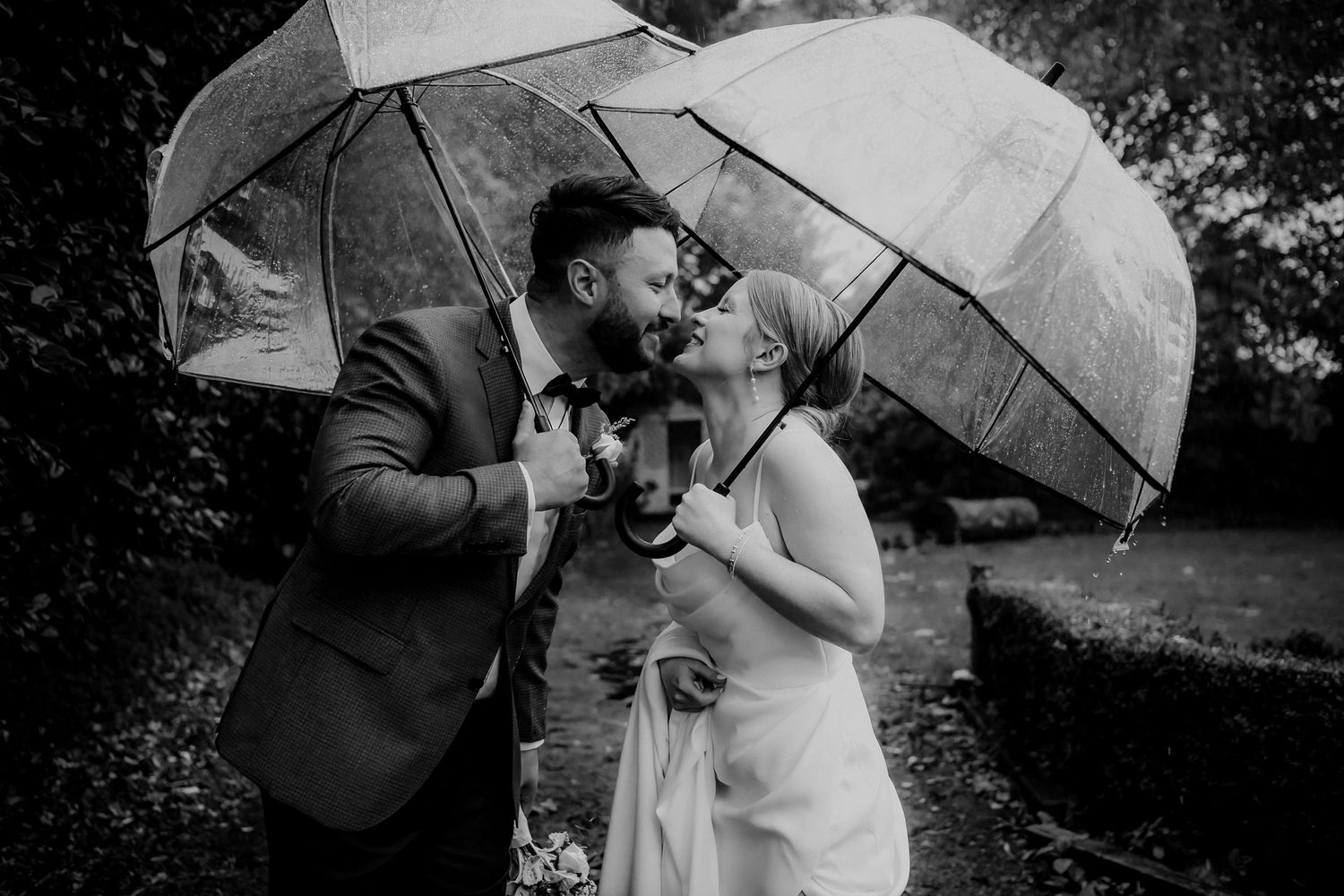 Black and White of Bride and Groom kissing under umbrellas in the rain at Tarureka Estate captured by August and Vine