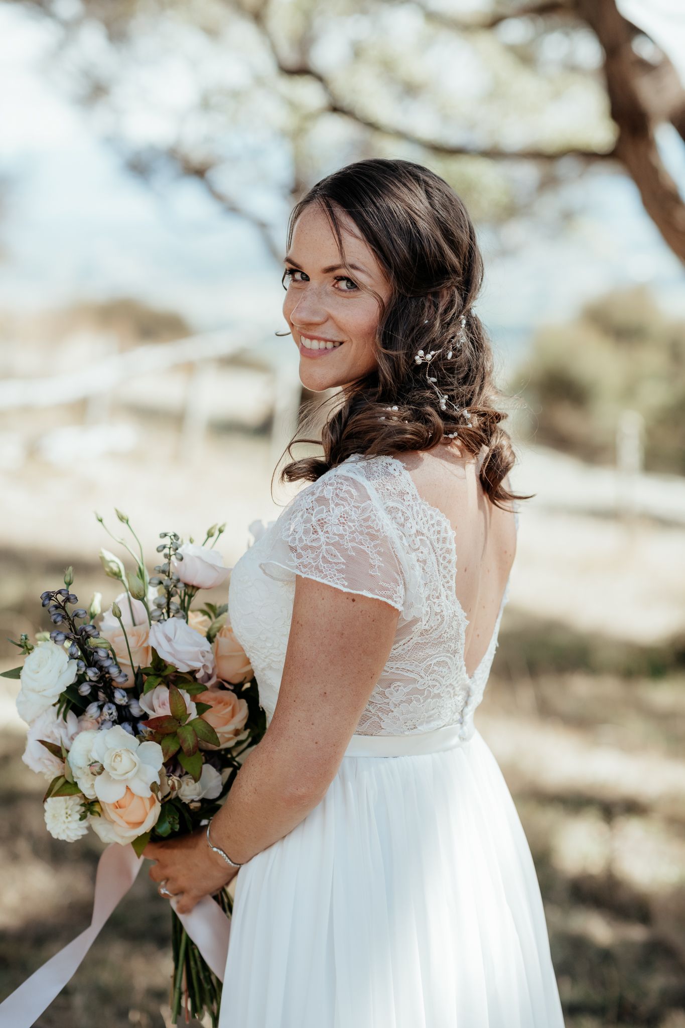 Beautiful outdoor bridal portrait showing elegant lace gown and romantic mixed pastel bouquet in natural sunlight by August and Vine