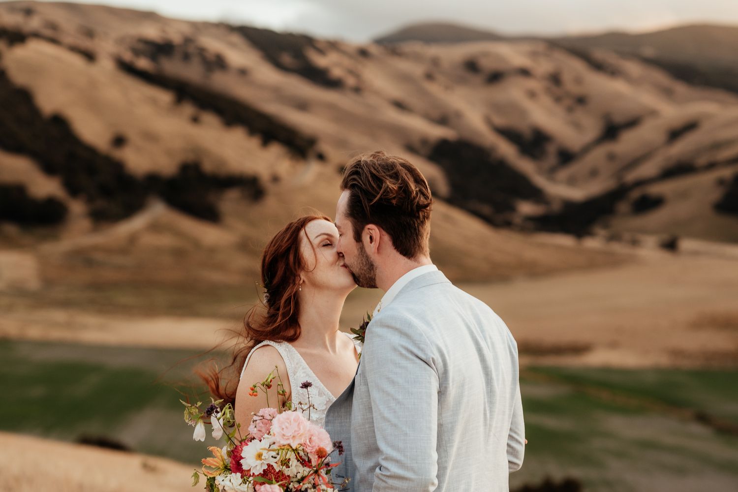 Bride and Groom kiss on golden hilltop at sunset at Tironui Farm by August and Vine
