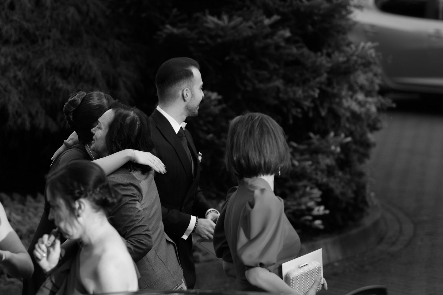 Blurry black and white vintage photograph of people walking together outdoors with trees in background.