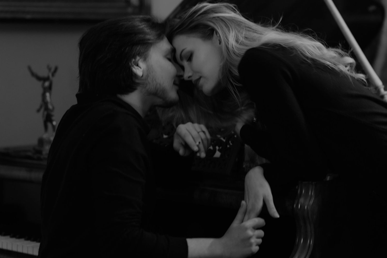 Two people share an intimate moment in black and white as they lean in close together.