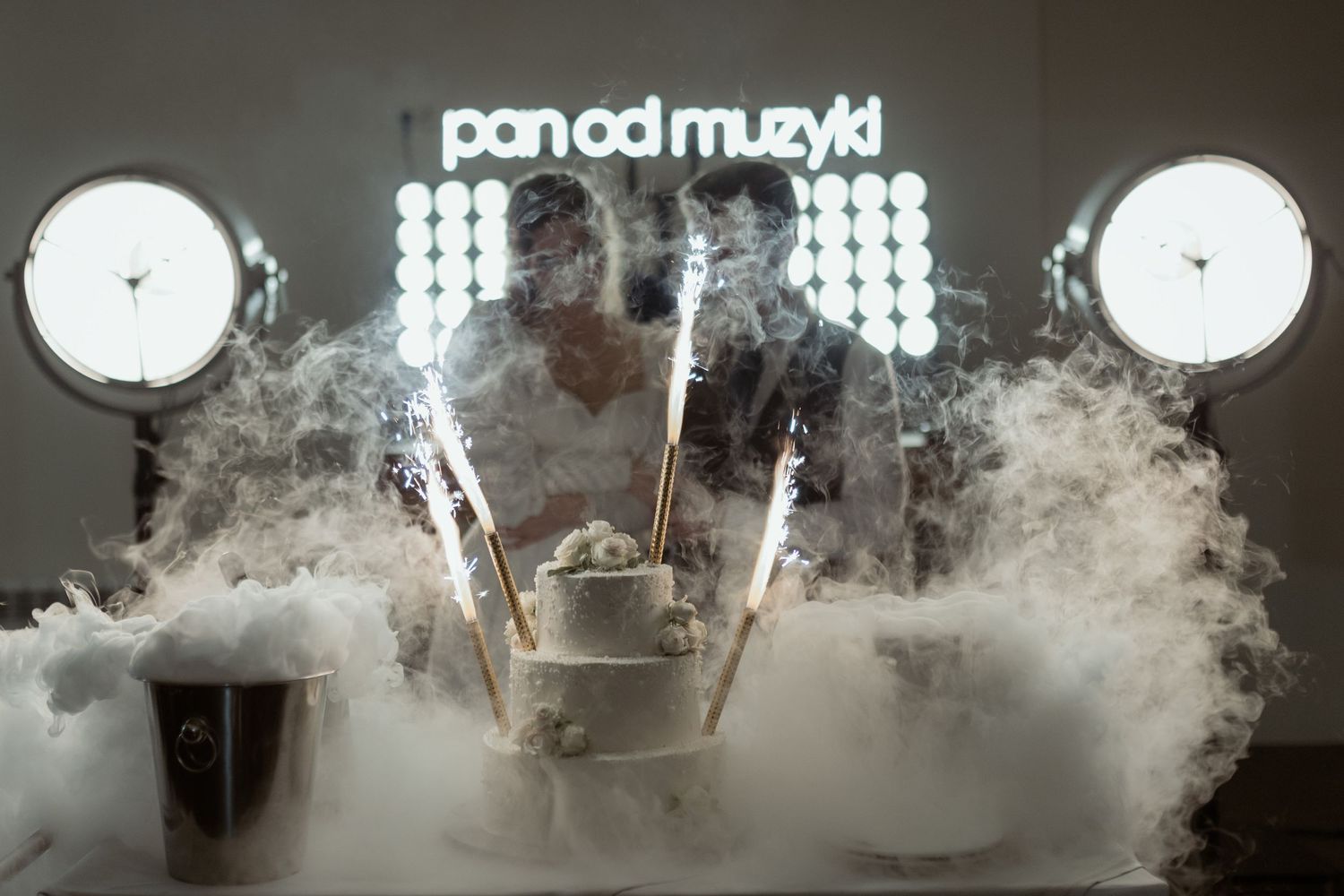 A DJ booth emerges through theatrical smoke with glowing lights and 'pan od muzyki' text illuminated above.