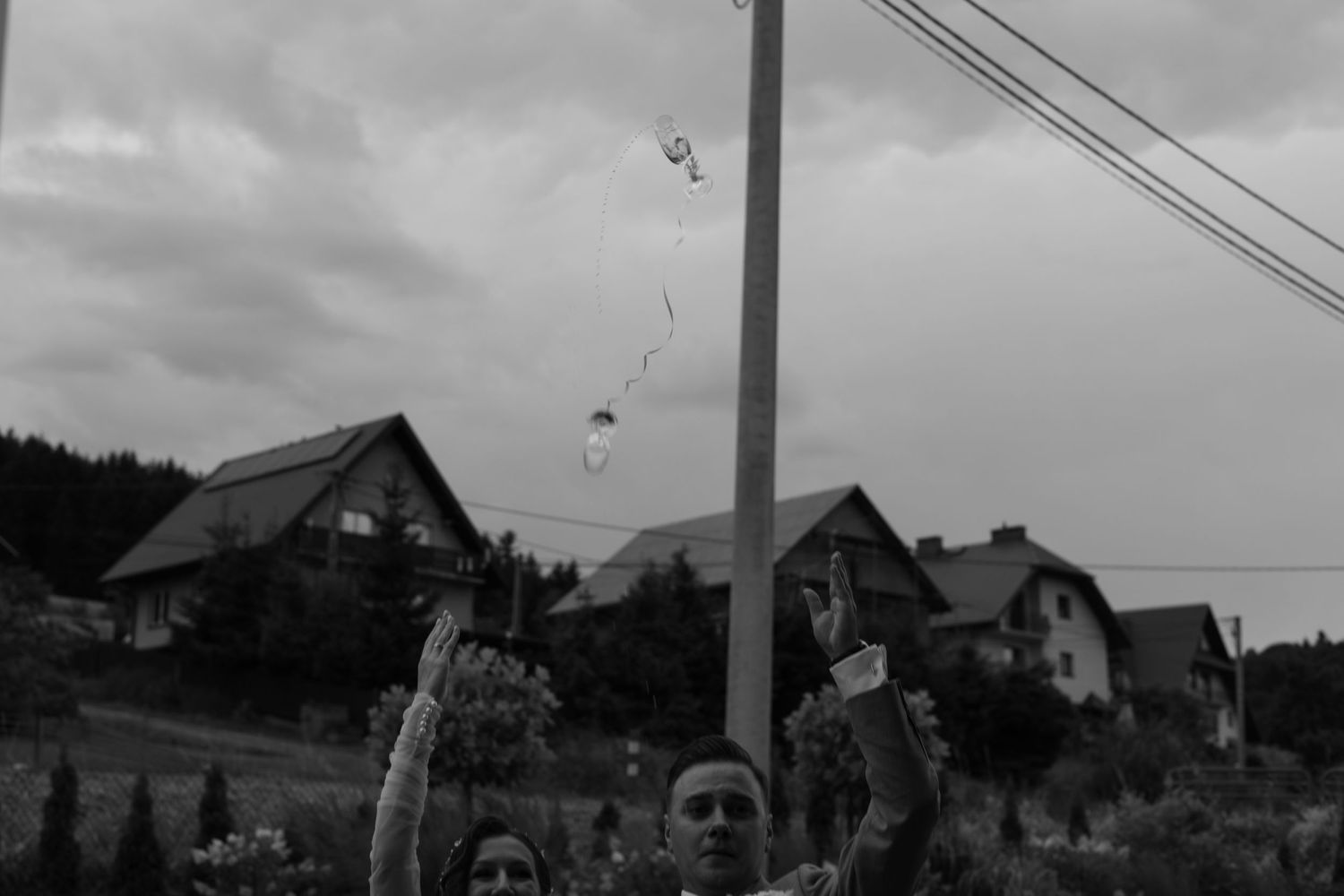 A black and white photo shows bubbles floating in front of houses on a hillside with power lines overhead.