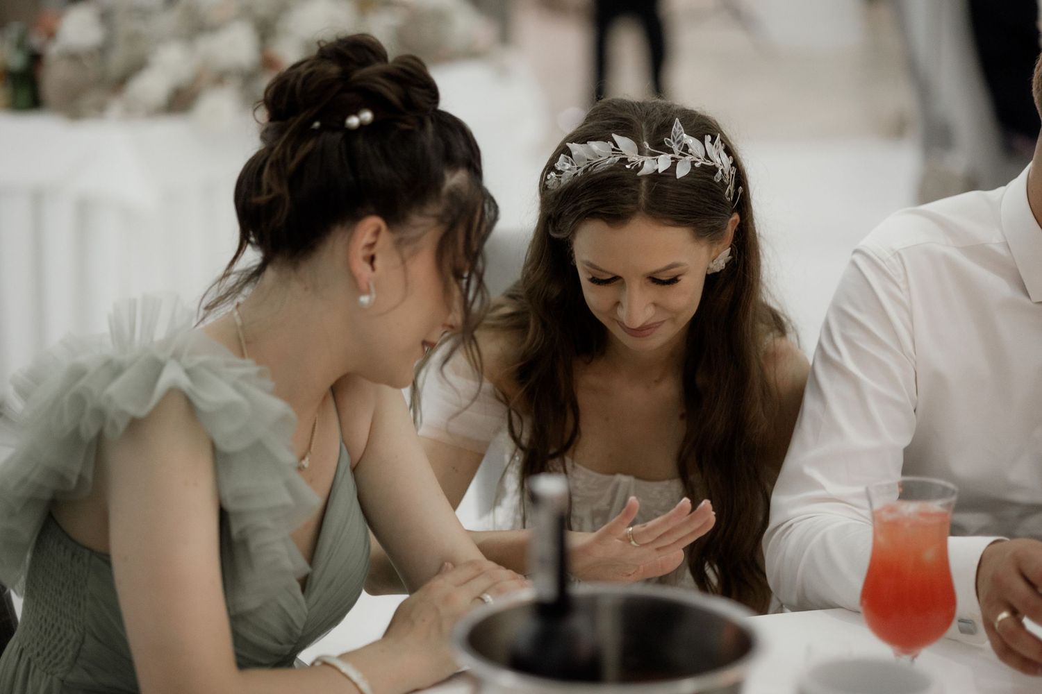Two guests share a moment at an elegant wedding reception table with drinks and place settings.