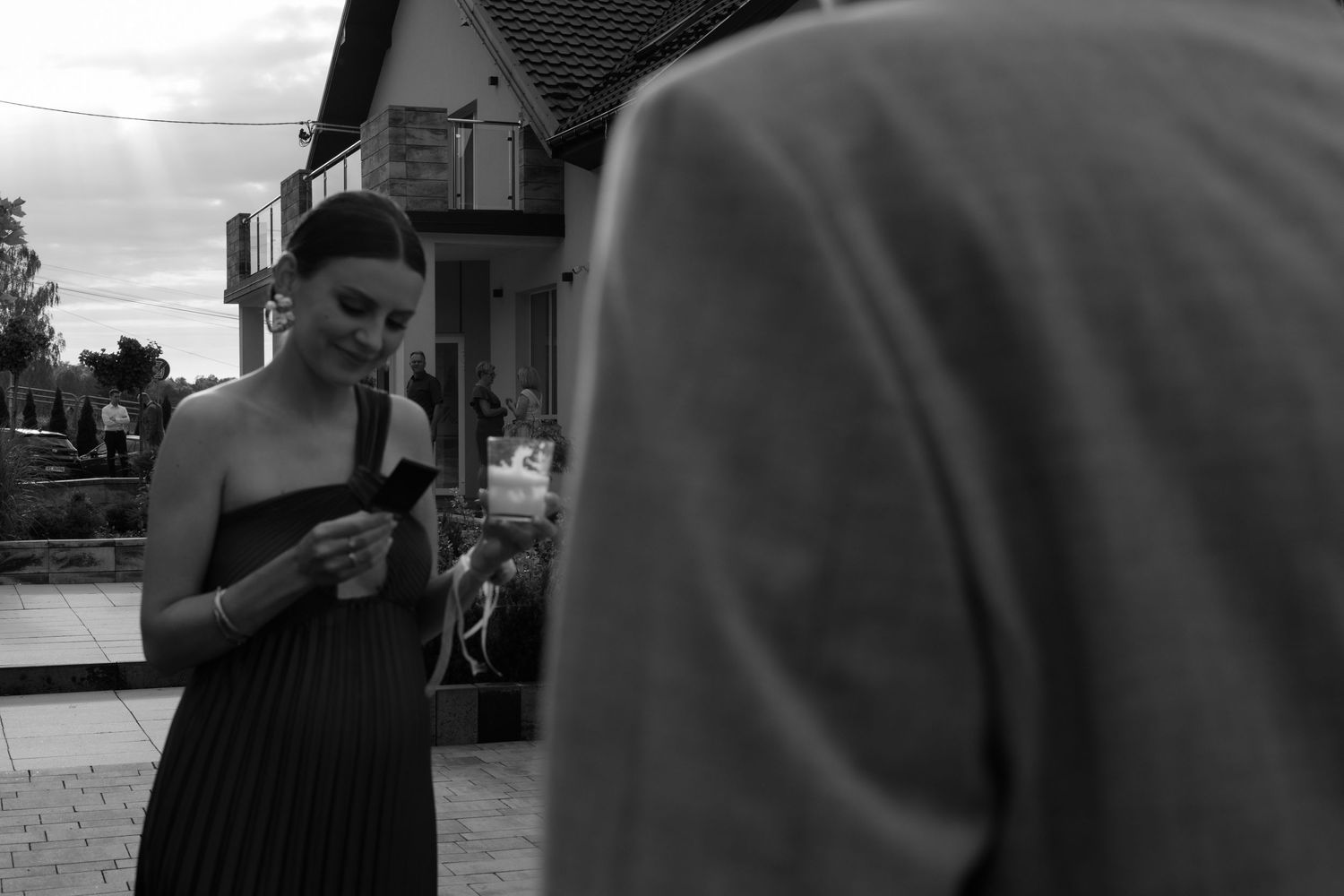 A person in a striped dress checks their phone on a city street, captured in black and white photography.