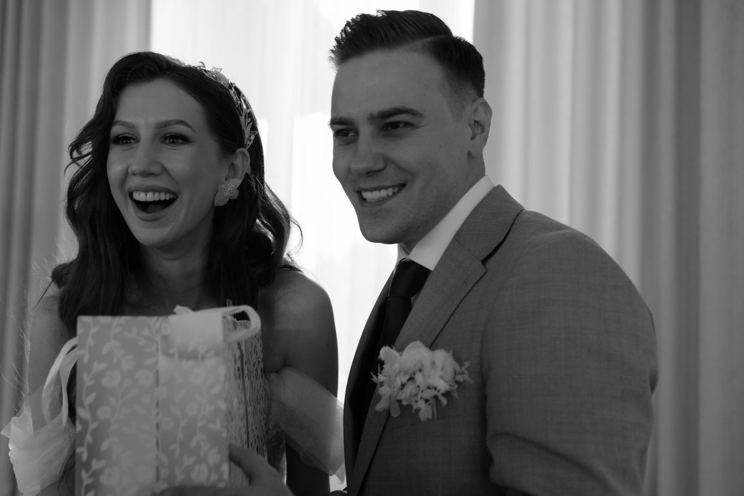 Black and white photo of a happy couple laughing together during what appears to be a wedding ceremony.