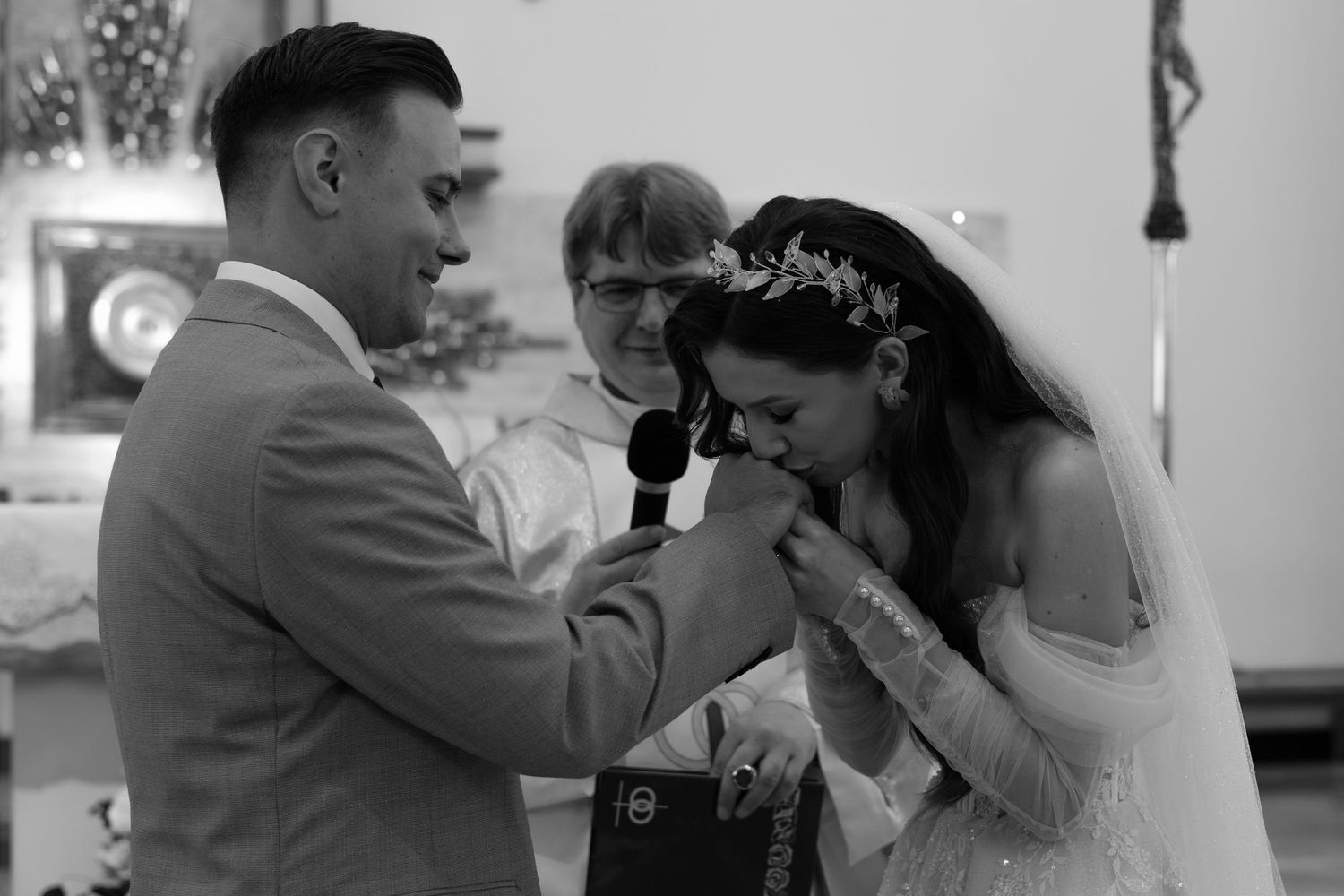 A couple shares an emotional moment at their wedding ceremony as the bride kisses the groom's hand during their vows.