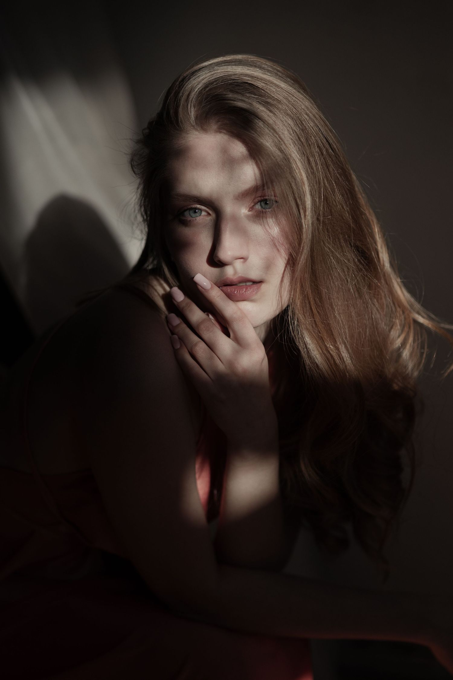 Moody portrait with dramatic shadows and natural window lighting.