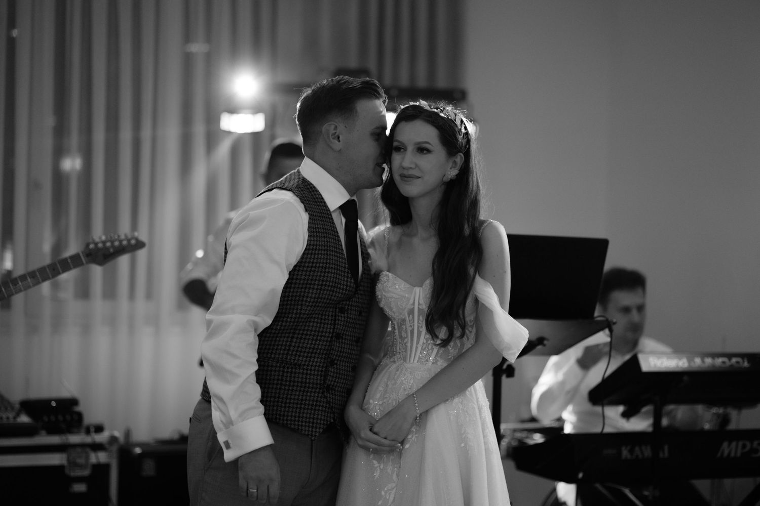 A romantic black and white wedding reception scene with a couple sharing a tender moment on the dance floor.