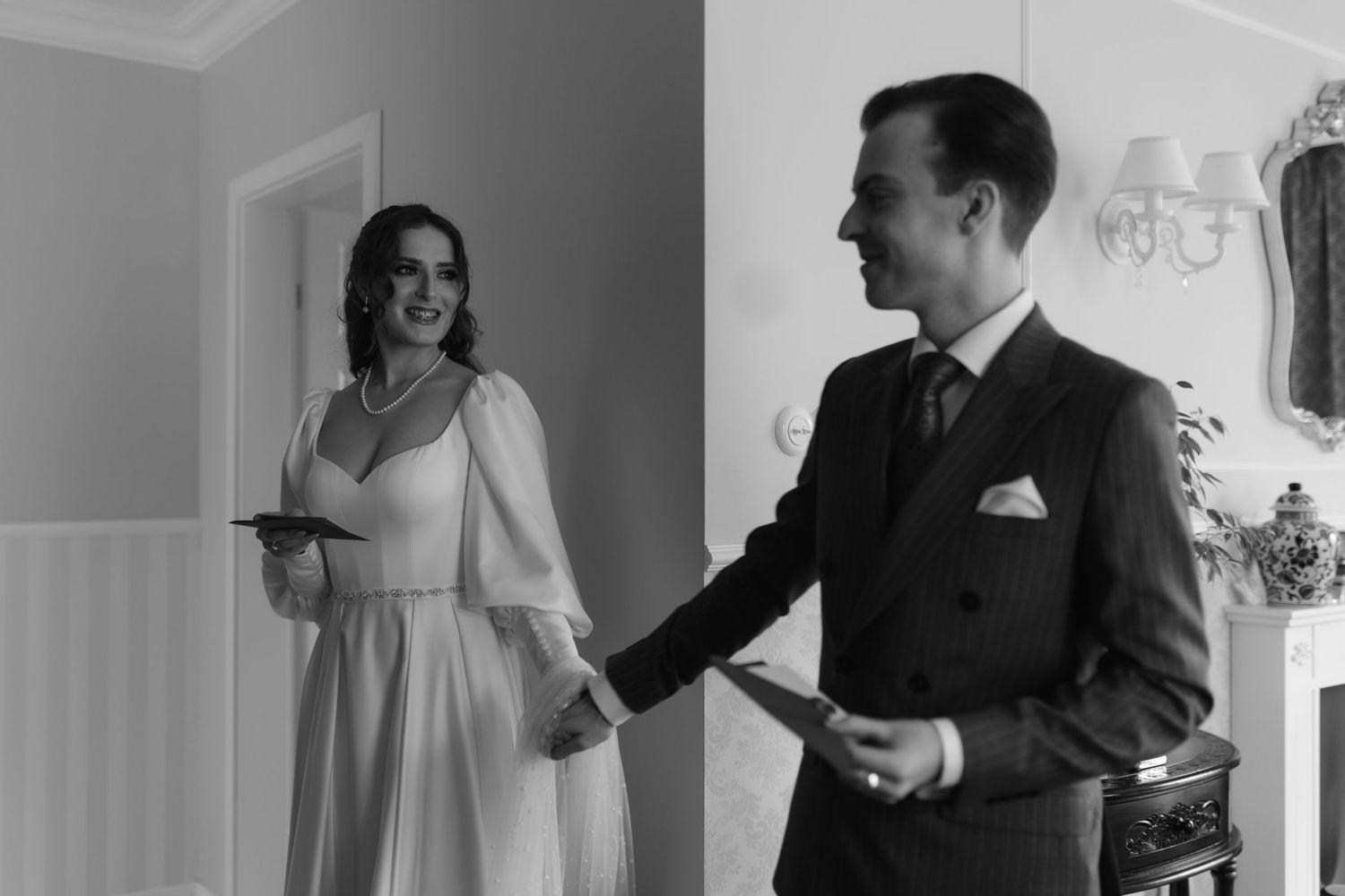 Black and white photo showing a first look between a bride in a white dress and groom in a dark suit.