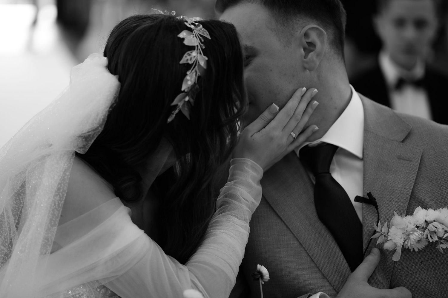 Black and white photo of tender moment between newlyweds whispering during wedding ceremony.