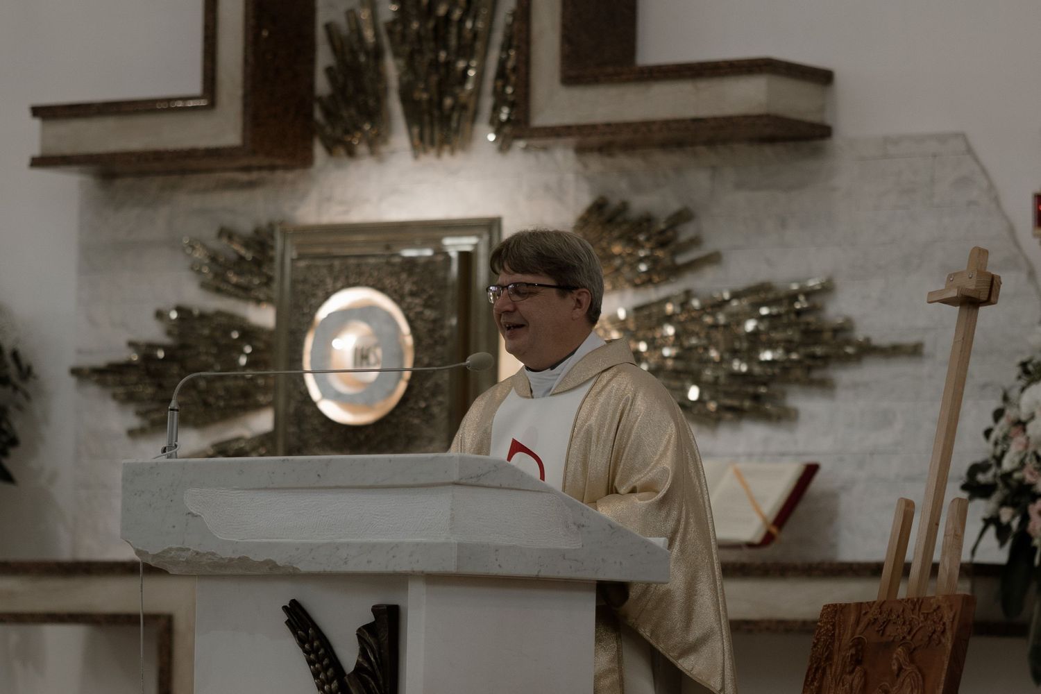 A church service taking place with a podium and cross visible in a dimly lit sanctuary.