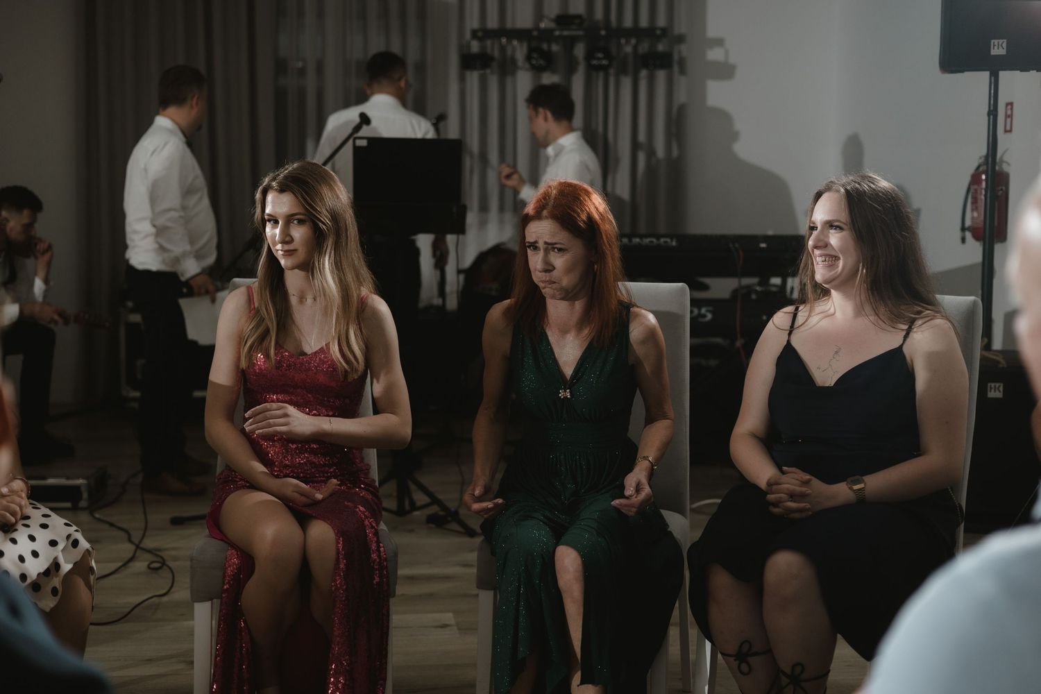 Three people seated together wearing evening attire during what appears to be a formal event or performance.