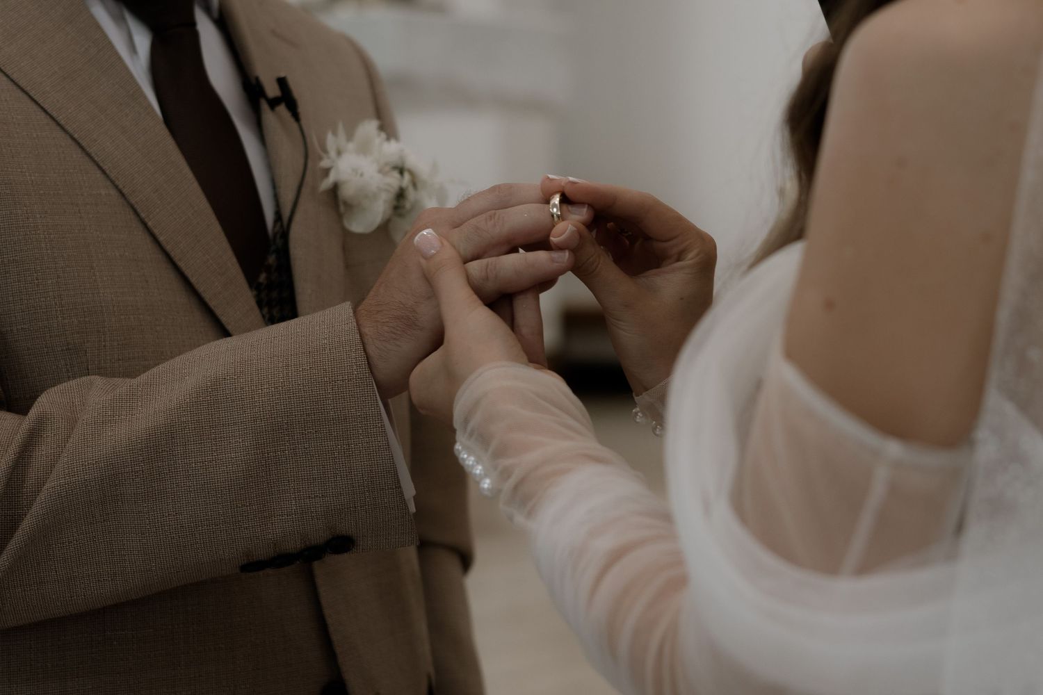Close-up view of hands exchanging wedding rings during an intimate ceremony.