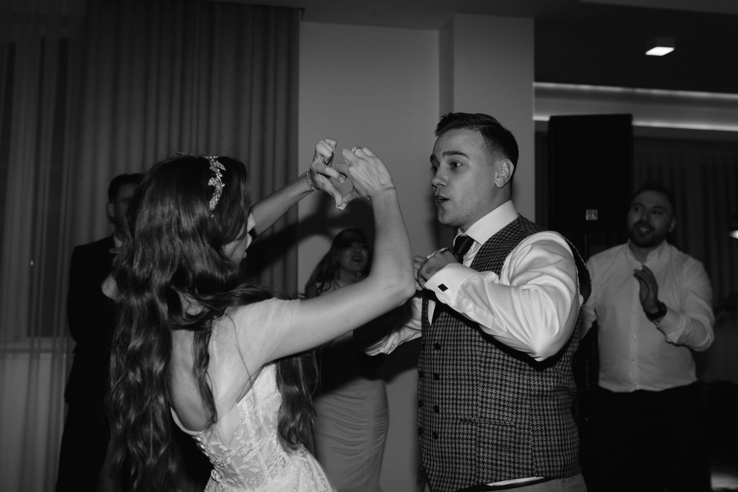 A couple dancing together at their wedding reception in elegant formal attire shown in black and white photography.