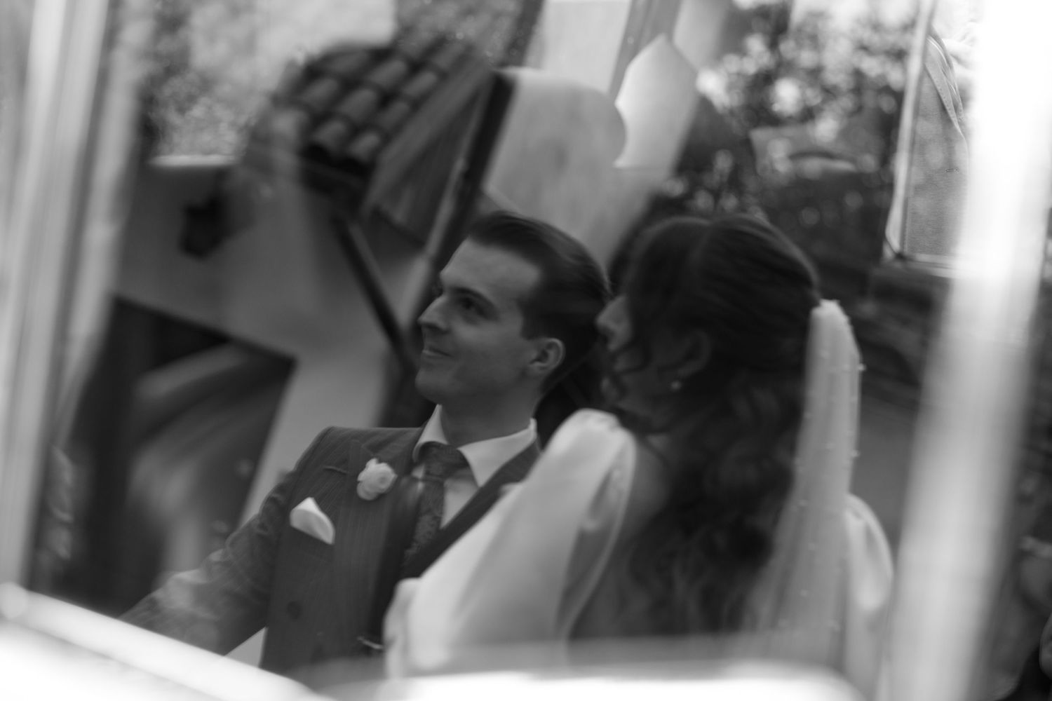 A black and white photograph showing a couple in formal attire during what appears to be a wedding ceremony.