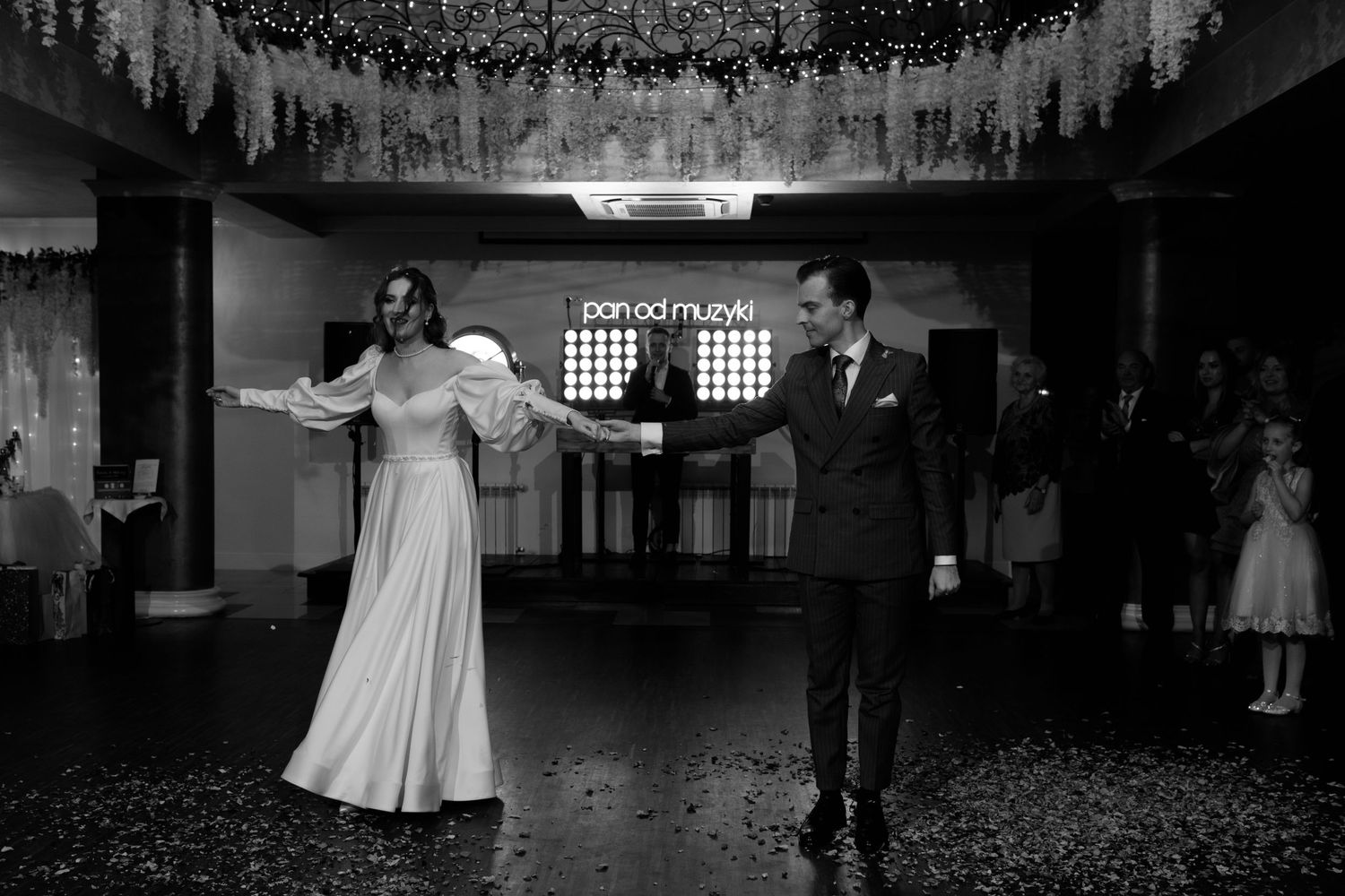 A couple shares their first dance under decorative ceiling drapes at a wedding reception venue.