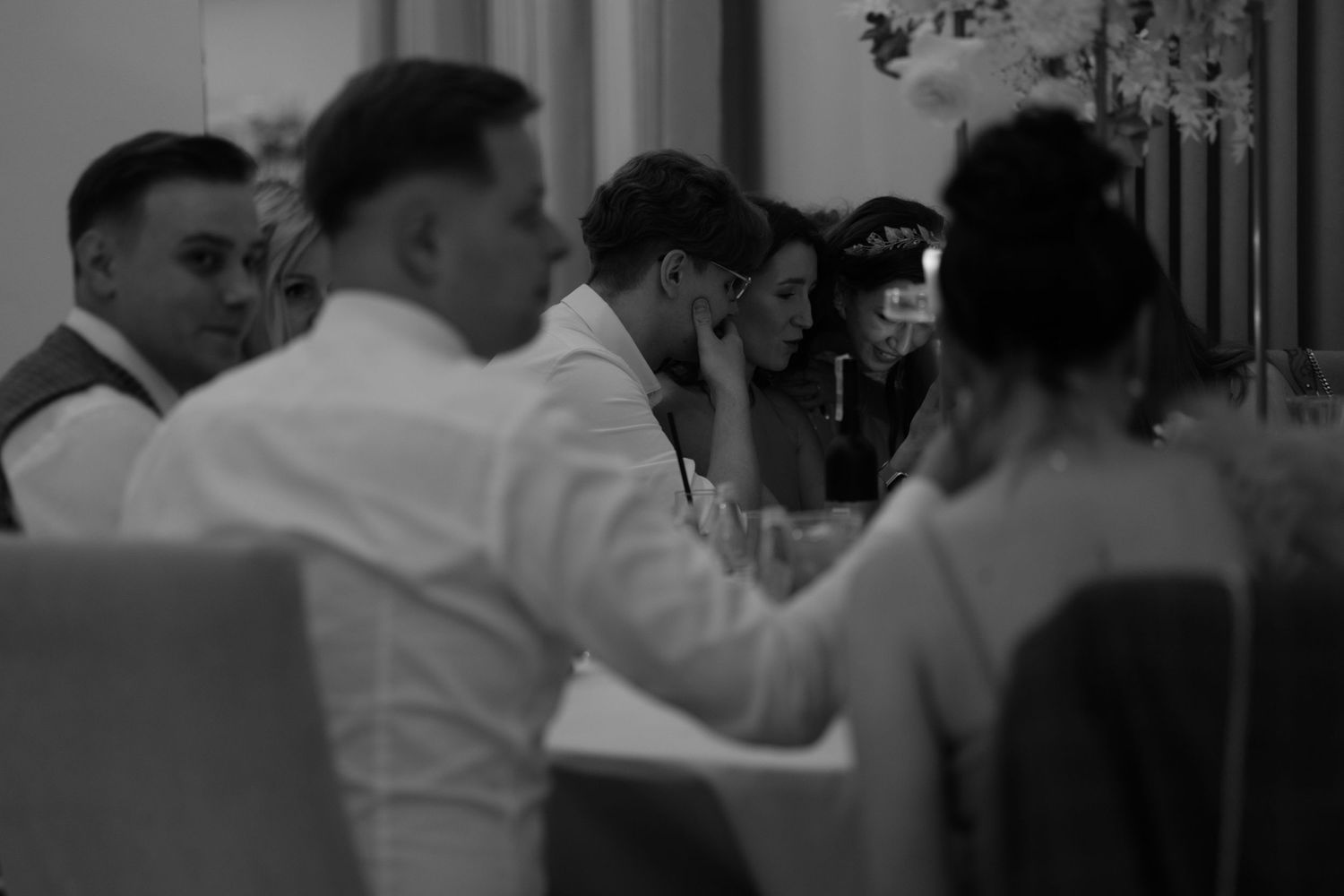 A black and white photograph of people seated at a table during what appears to be a formal gathering or dinner event.