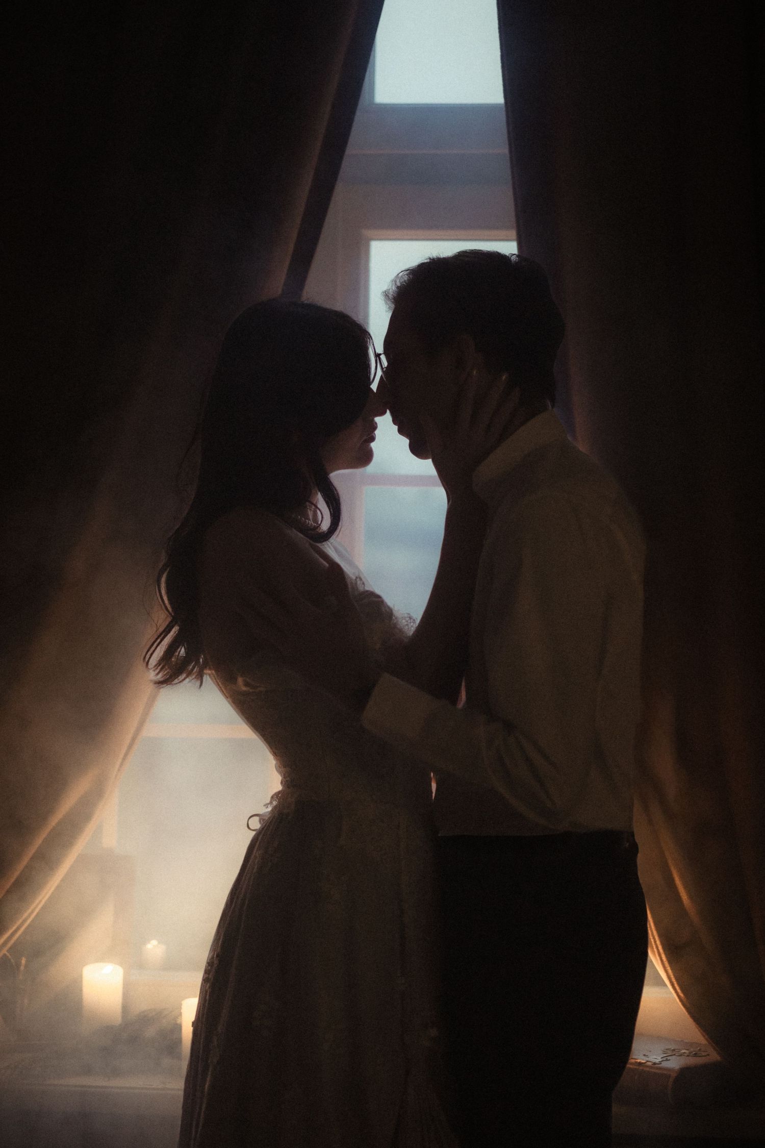 Silhouettes of a romantic couple in backlit window light creating an intimate atmospheric series of poses.