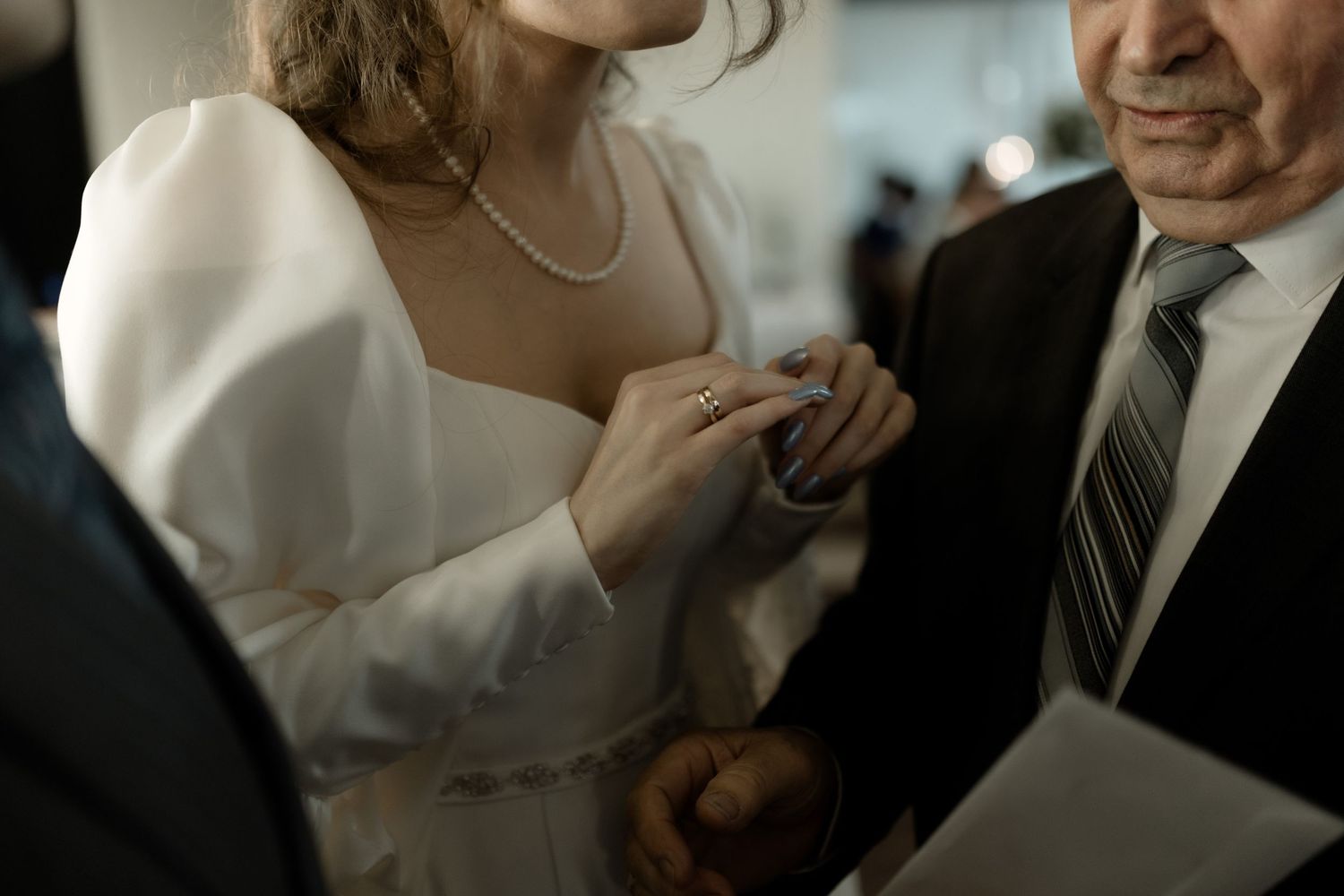 Close-up of hands and formal attire during what appears to be a wedding or formal event.