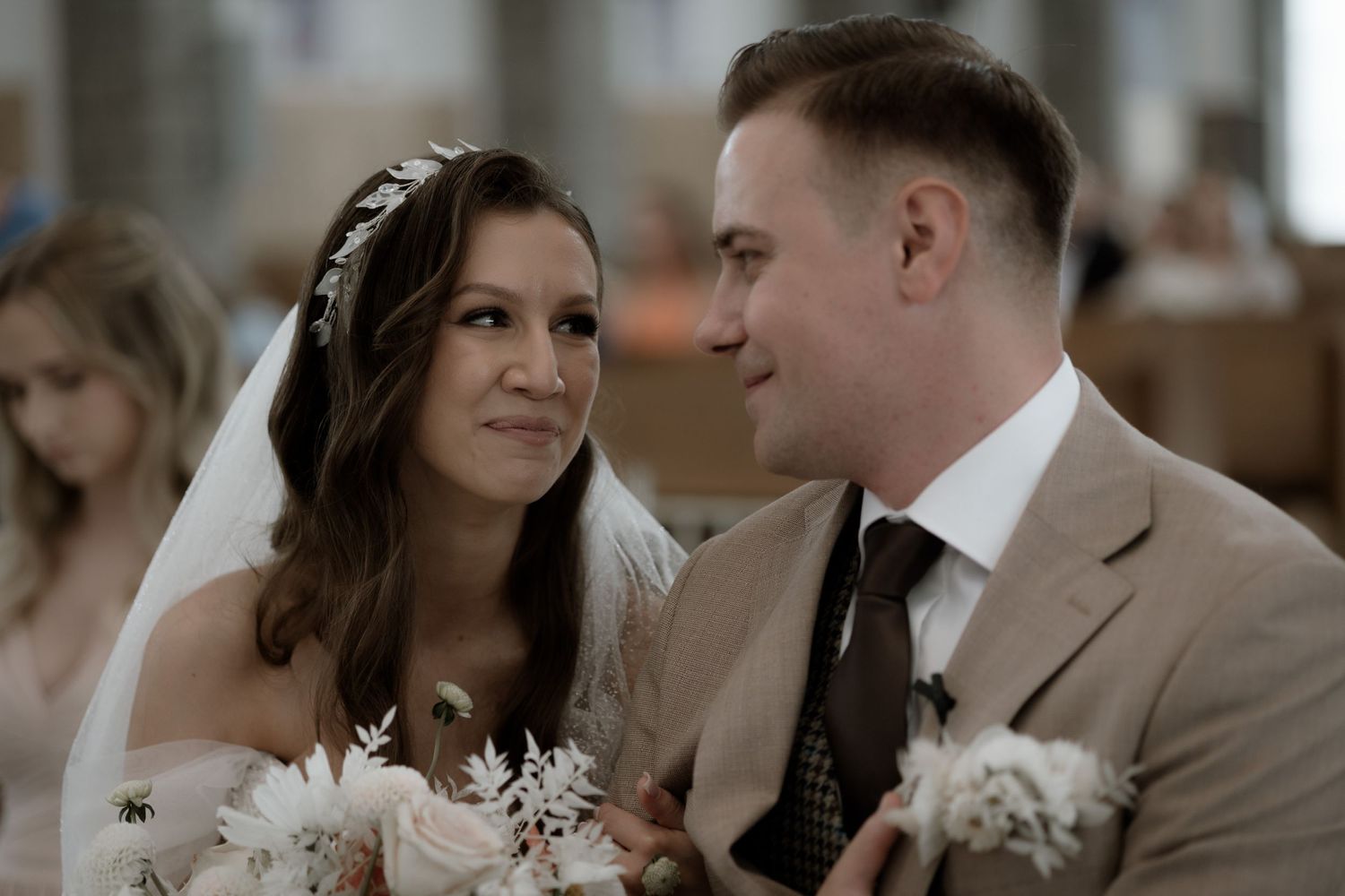 A couple shares a tender moment during their wedding ceremony while wearing traditional wedding attire.