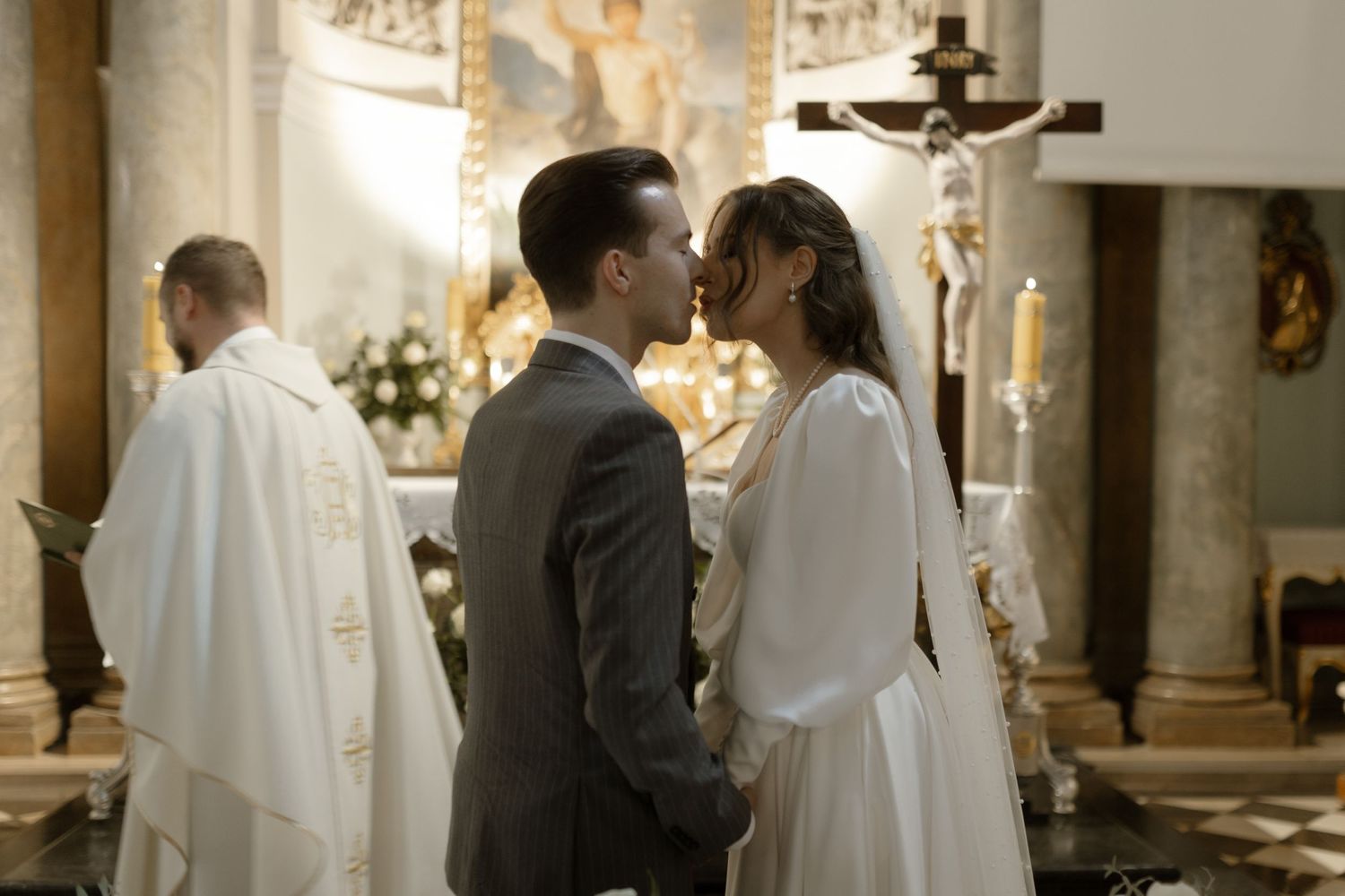 A bride and groom share an intimate moment during their wedding ceremony in a traditional church with ornate decor.