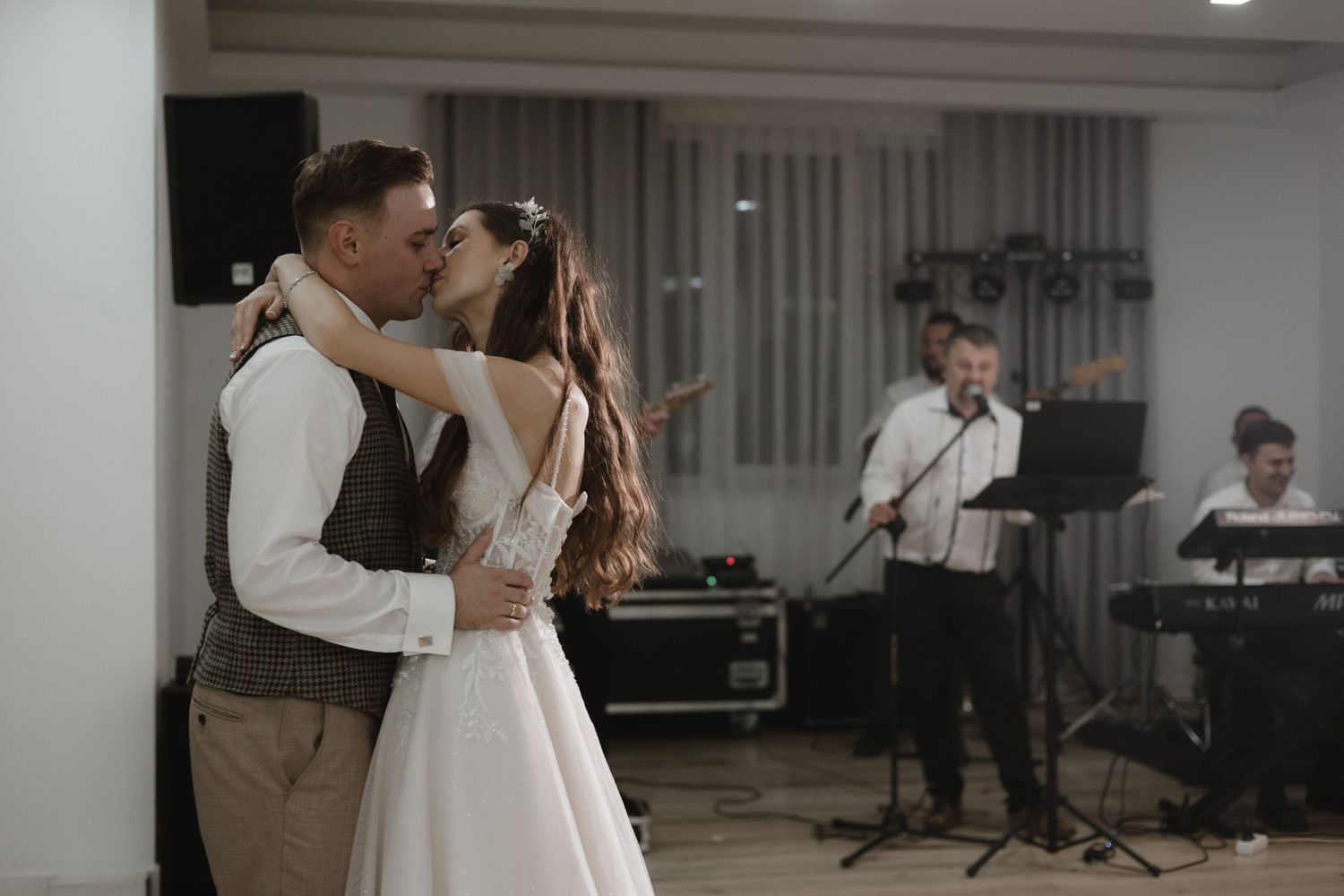 A couple shares their first dance at a wedding with musicians performing in the background.