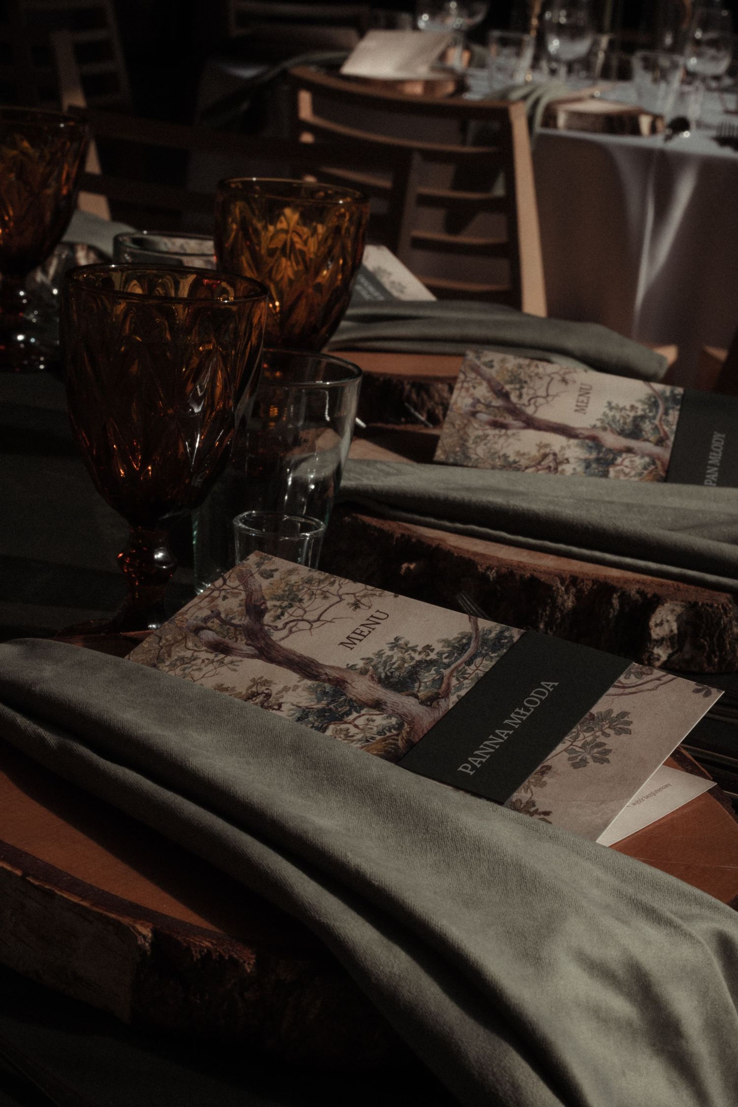 Elegant table settings with floral print placemats and amber glassware in a dimly lit restaurant interior.