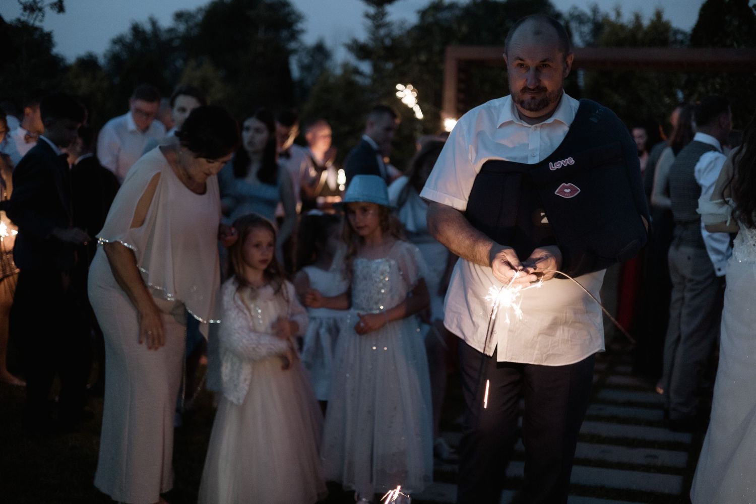 A group gathers at dusk for a candlelight ceremony with illuminated candles creating a soft glow in the darkness.